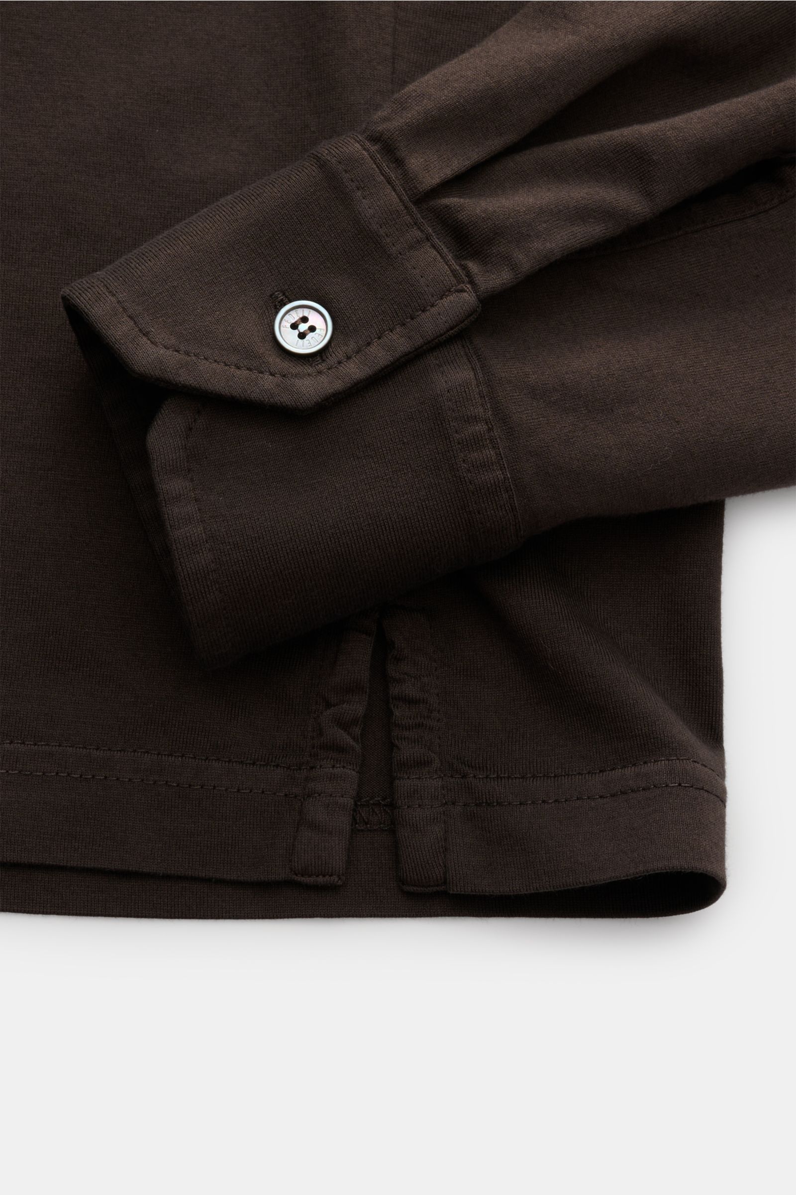 Nahaufnahme des Fedeli Jersey Longsleeve-Poloshirt 'Zero' braun, seitlich fotografiert, zeigt Perlmuttknopf, Sportmanschette und Saumschlitze aus glattem, seidigem Giza-Baumwoll-Jersey.