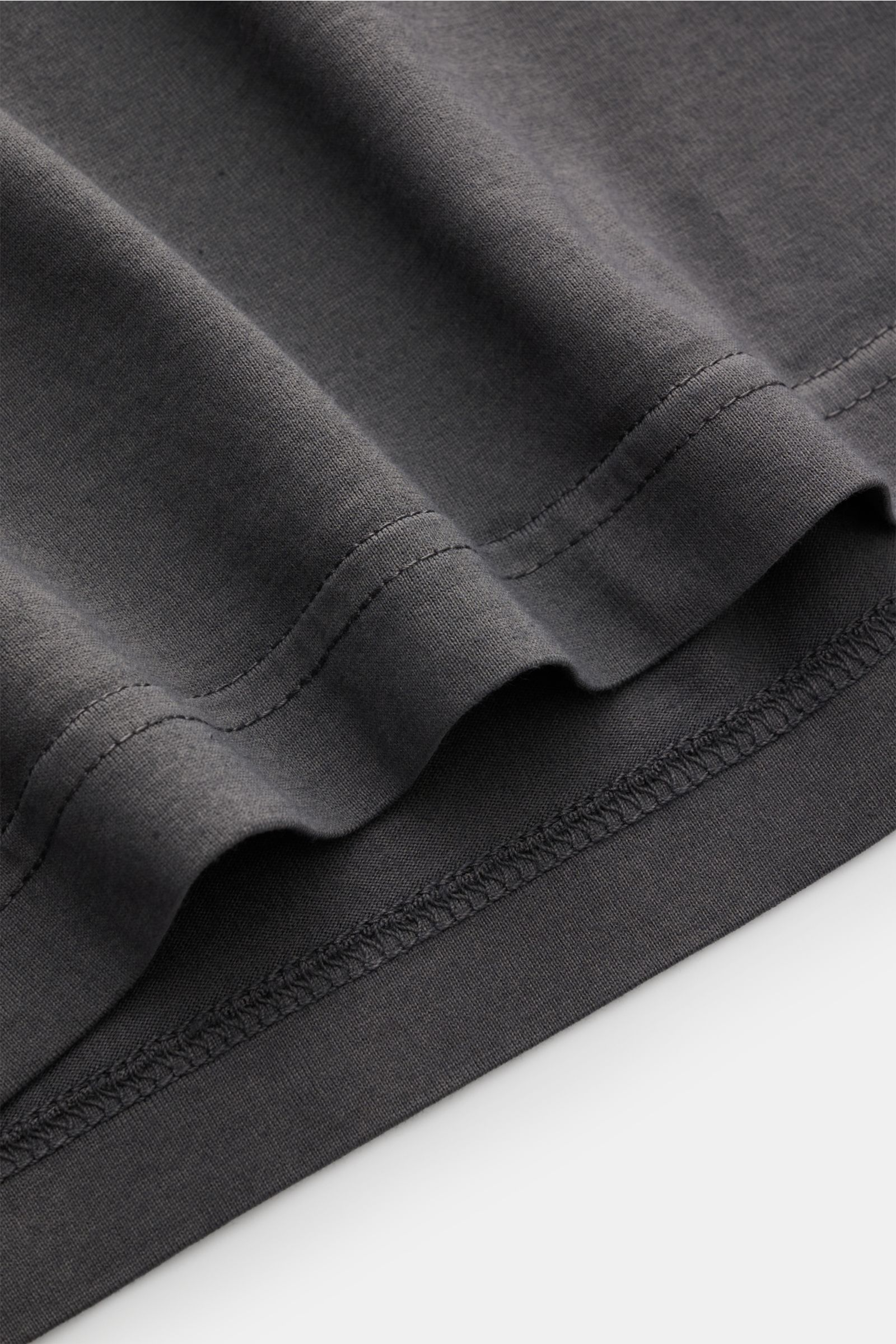 Nahaufnahme des Saums vom Fedeli Jersey Longsleeve-Poloshirt 'Zero' dunkelgrau, gefertigt aus sanfter, nachhaltiger Giza-Baumwolle mit glattem, seidigem Griff, im Detail von unten fotografiert.