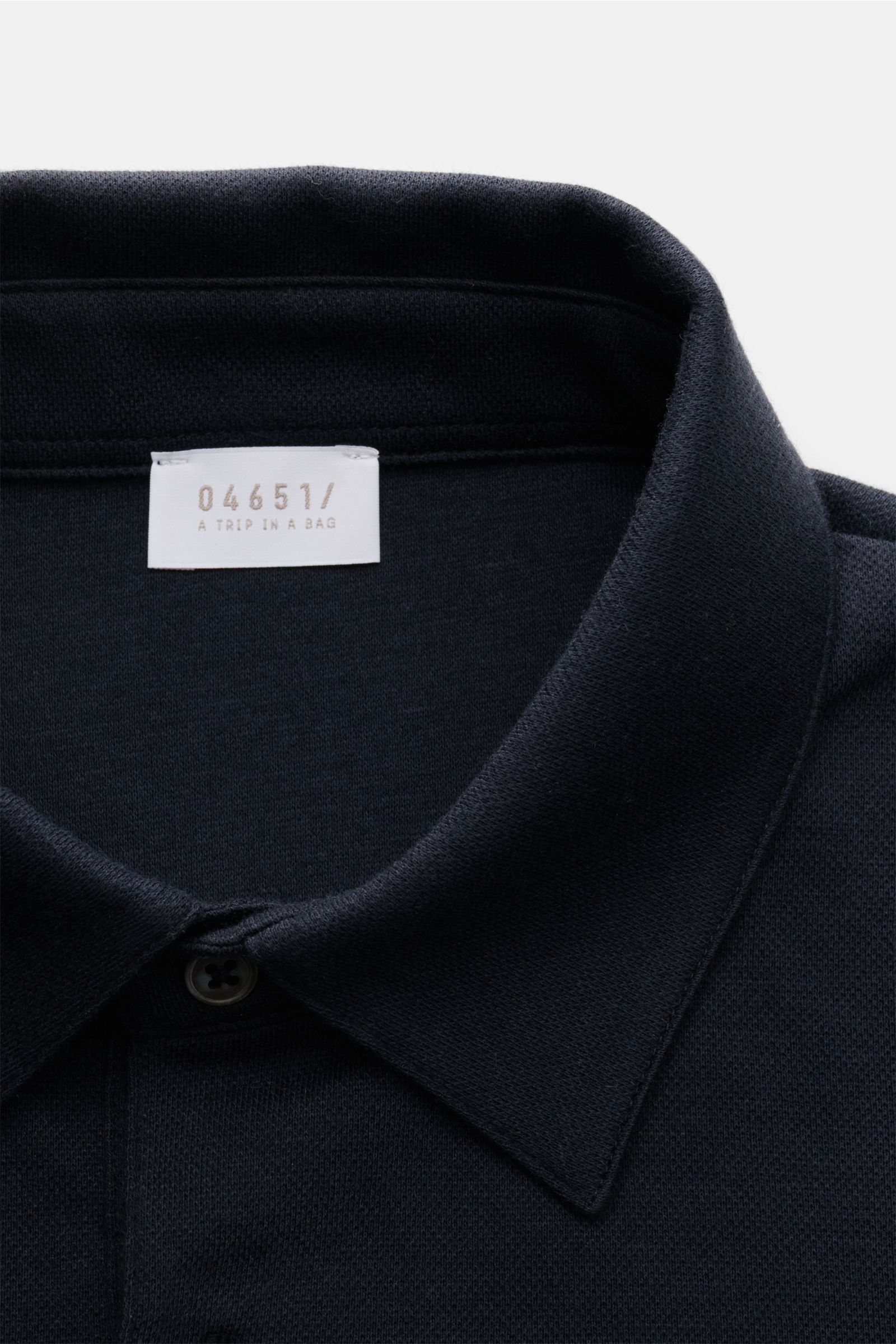 Close-up front view of the collar and label of the 04651/ A trip in a bag Longsleeve-Poloshirt dark navy in soft cotton-cashmere piqué jersey.

Dieses Longsleeve-Poloshirt von 04651/ A TRIP IN A BAG aus softem Piqué-Jersey wurde aus einem edlen Baumwol