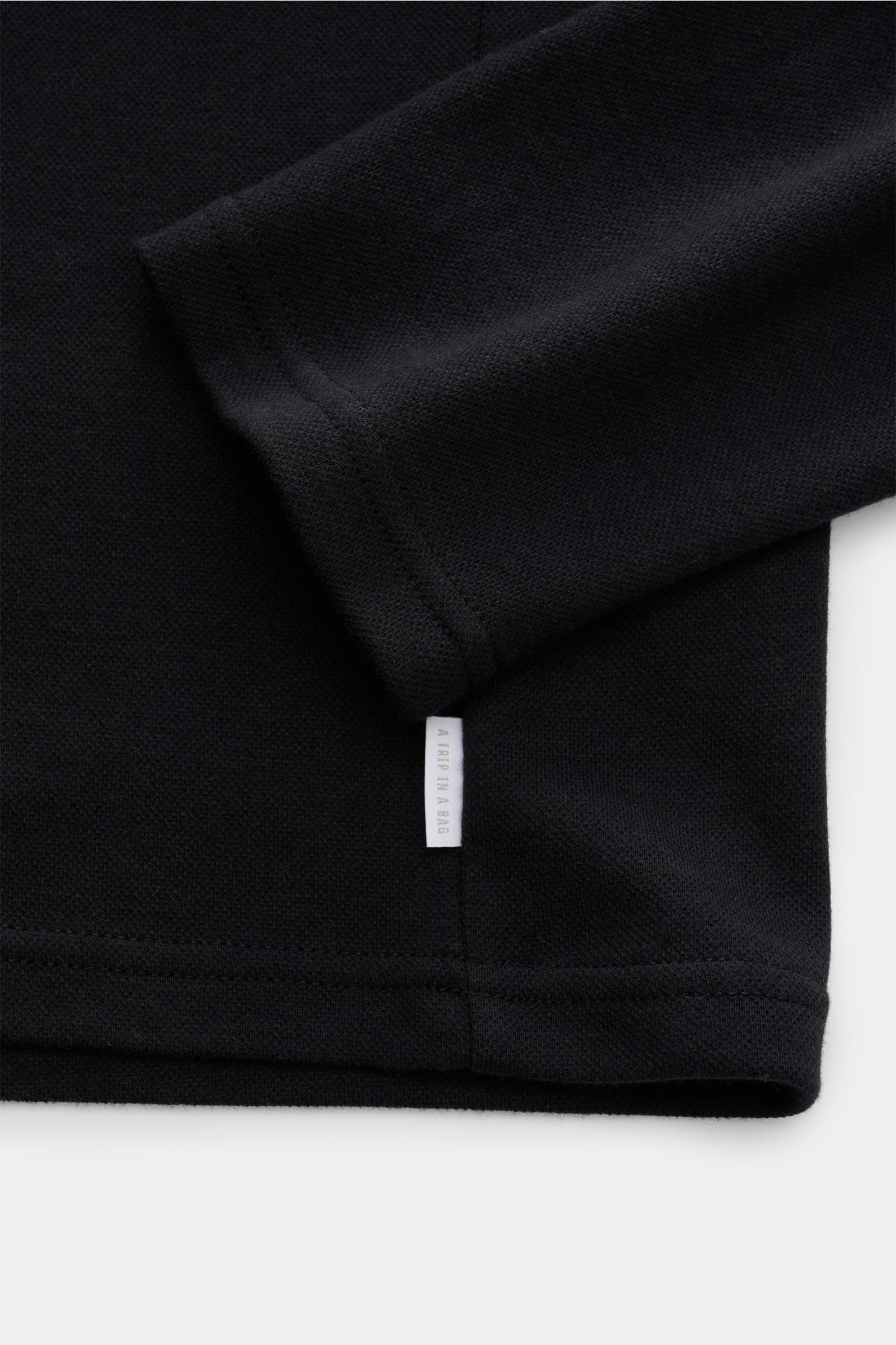 Schwarzes 04651/ A trip in a bag Longsleeve-Poloshirt aus Baumwoll-Cashmere-Piqué, Detailaufnahme Ärmel und Weblabel, weiche Qualität.