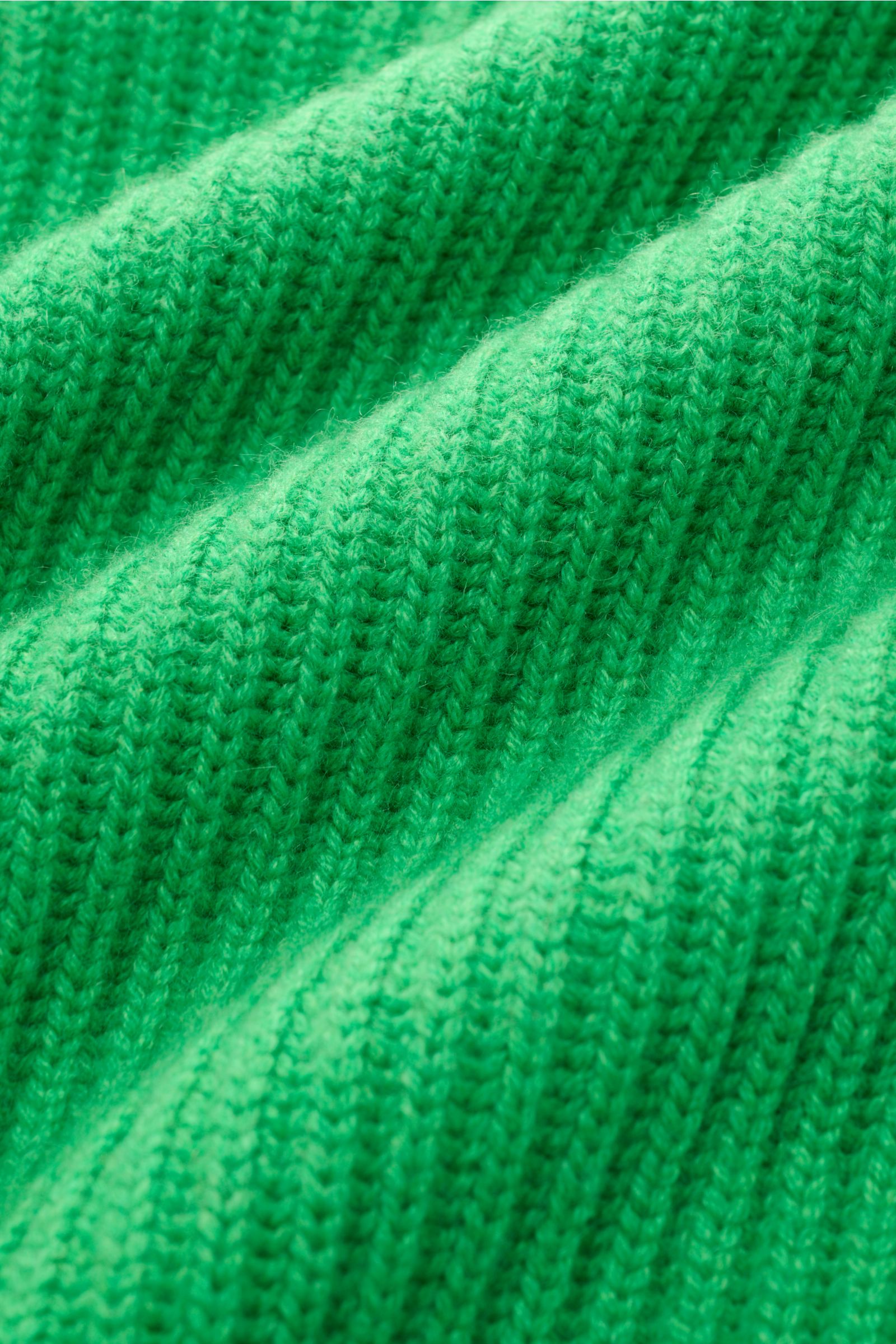 Nahaufnahme des grünen Malo Cashmere Strickpolo mit Patent-Strickmuster, reiner Cashmere, sehr weicher Griff, schwere Qualität, Oversized Fit, Drei-Knopf-Leiste, typischer Polokragen und elastischen Rippbündchen.