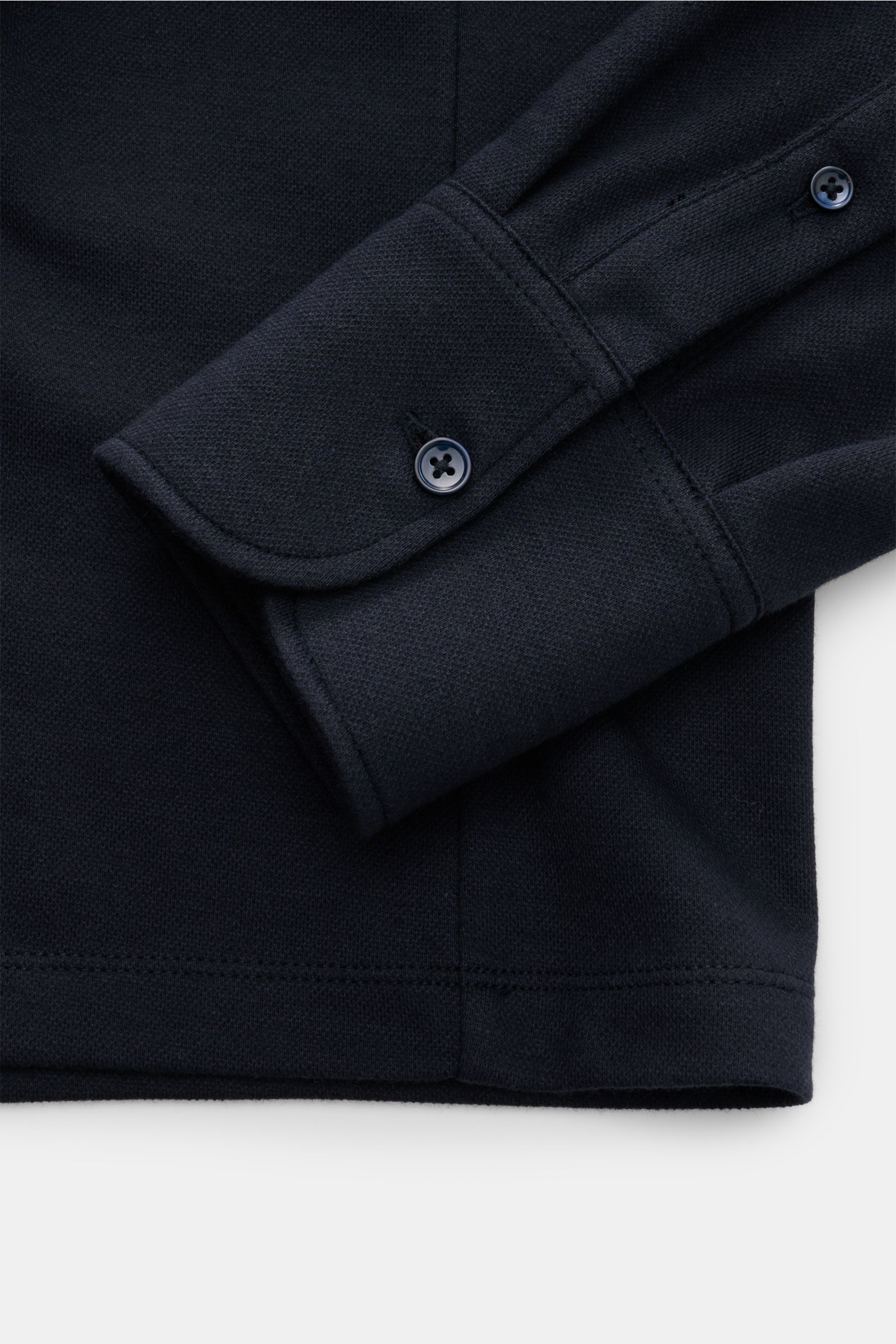 The Product is the Hero Longsleeve-Poloshirt navy, Piqué-Baumwoll-Cashmere-Mix, weicher Griff, Vier-Knopf-Leiste, Haifisch-Polokragen, Sportmanschette, Taillenabnäher, Saumschlitze, Detailaufnahme Ärmel und Saum von oben.