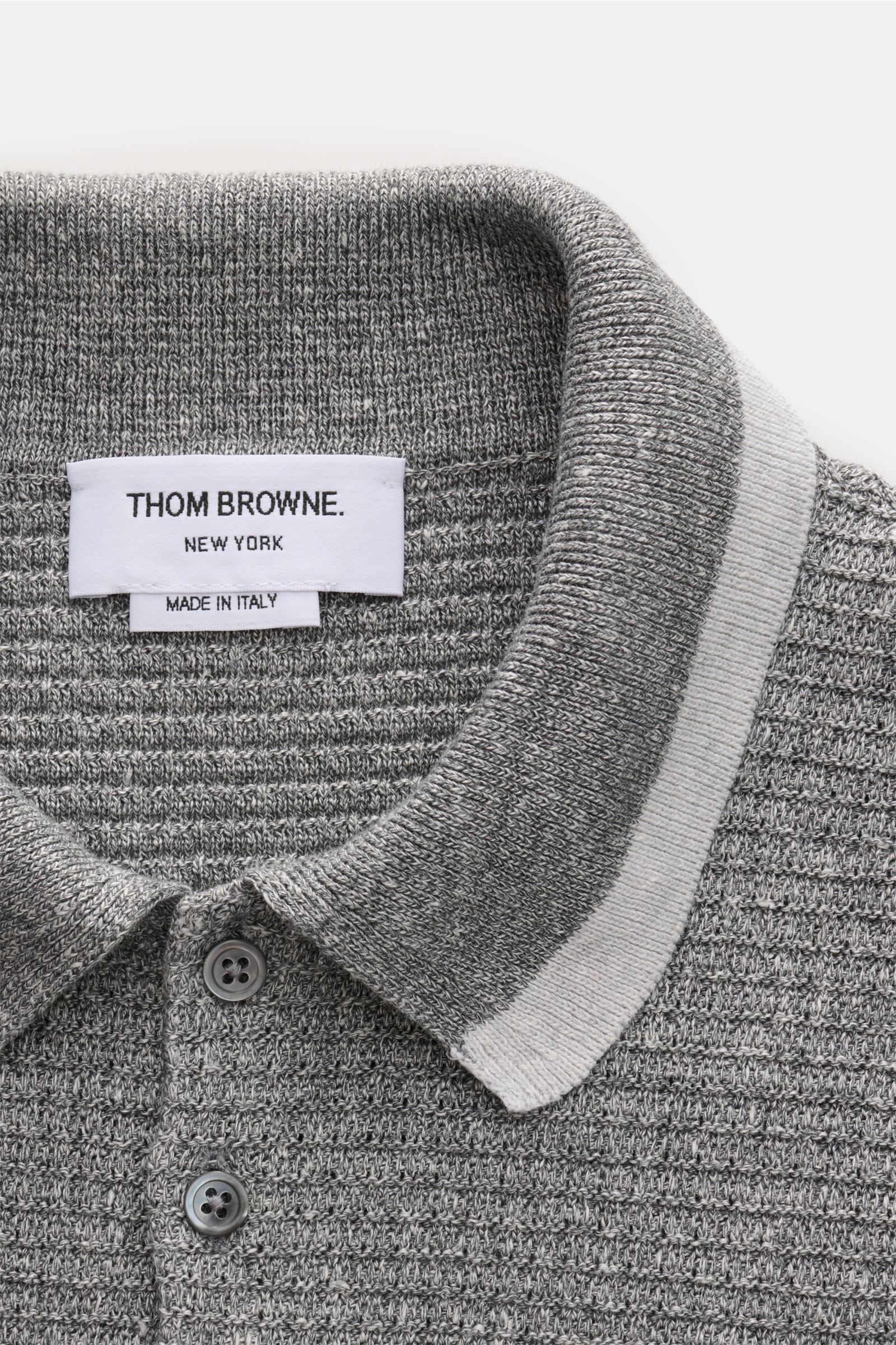 Close-up top-down view of the grey melange Thom Browne Strickpolo, showcasing its knitted collar, five-button placket, and textured knit pattern.
