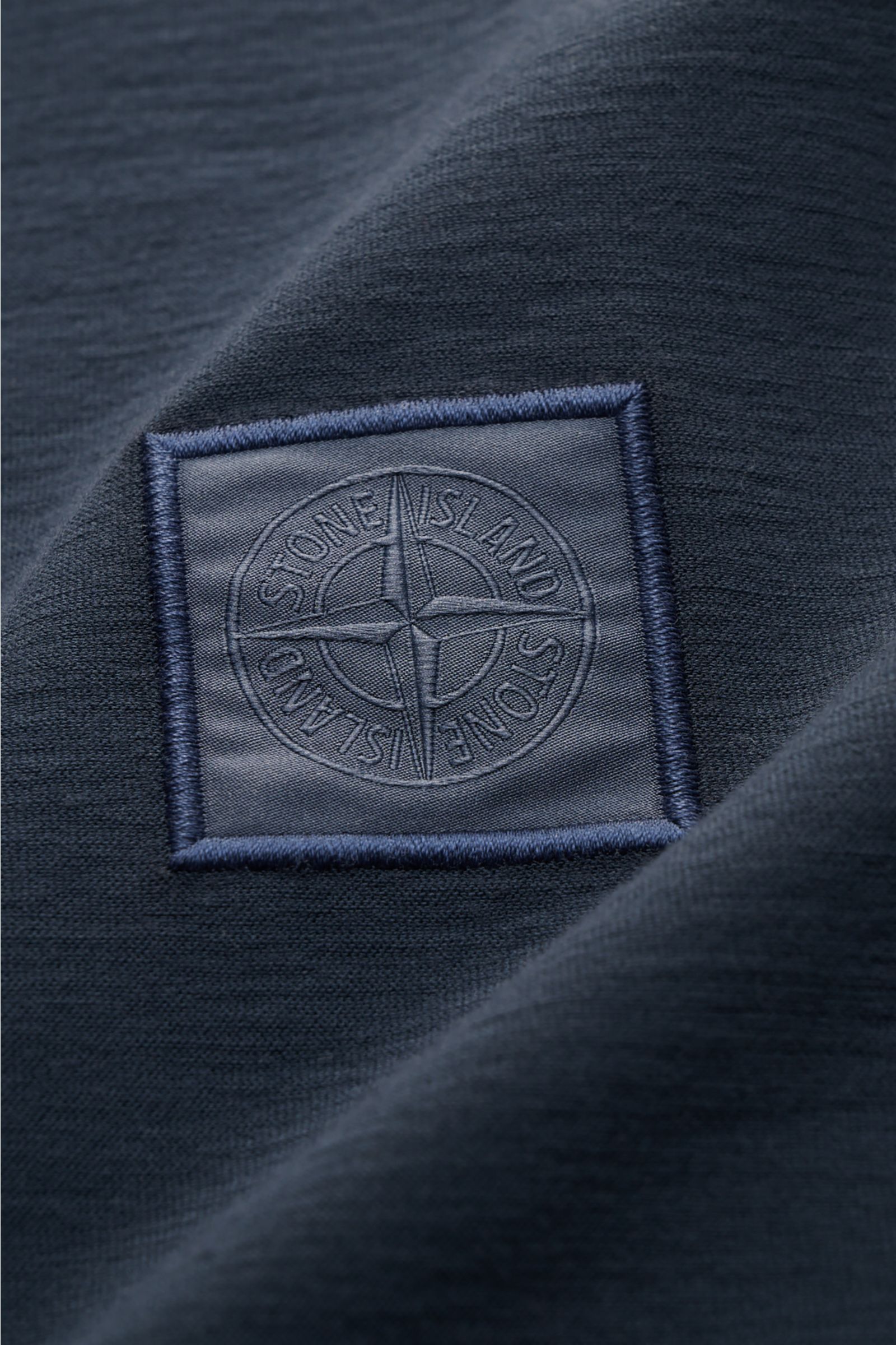 Stone Island Longsleeve-Poloshirt 'Ghost Piece' graublau, Detailaufnahme des tonalen Kompasslogos auf leicht griffiger Baumwoll-Jersey-Qualität.