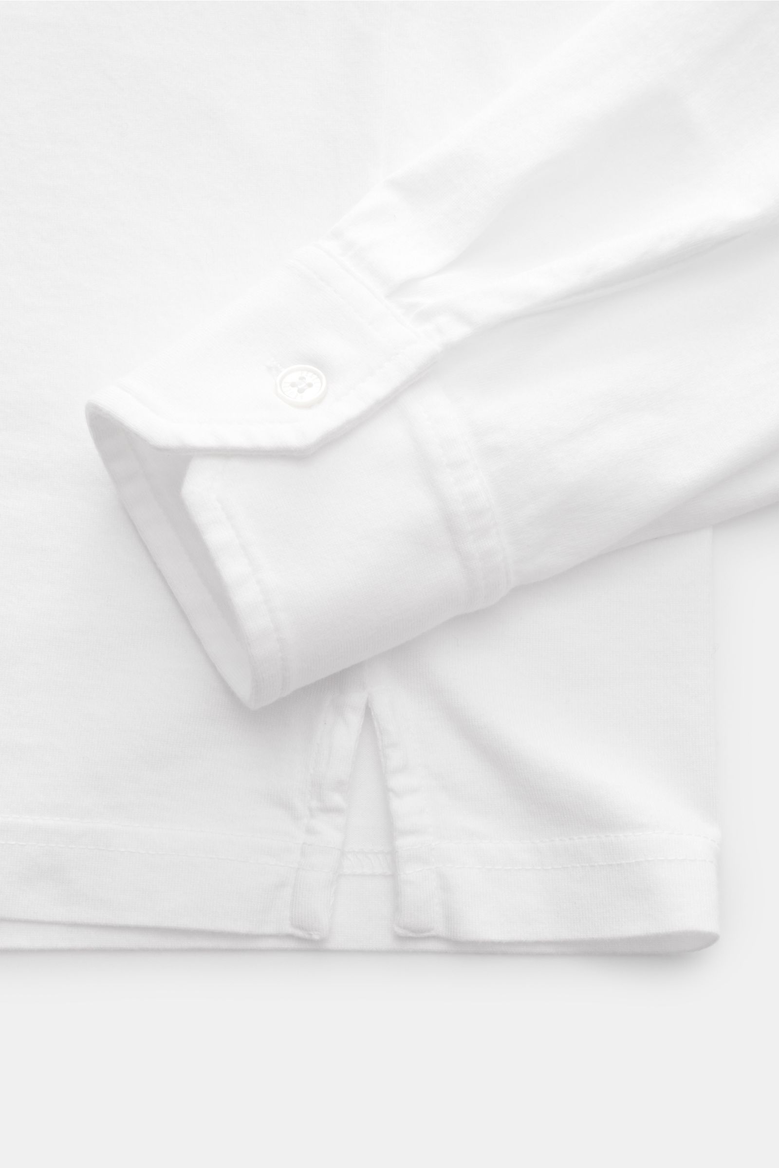 Fedeli Jersey Longsleeve-Poloshirt weiß, Detailaufnahme von Manschette und Saumschlitz, sanfter Griff, Giza-Baumwolle, Perlmuttknöpfe, Slim Fit.