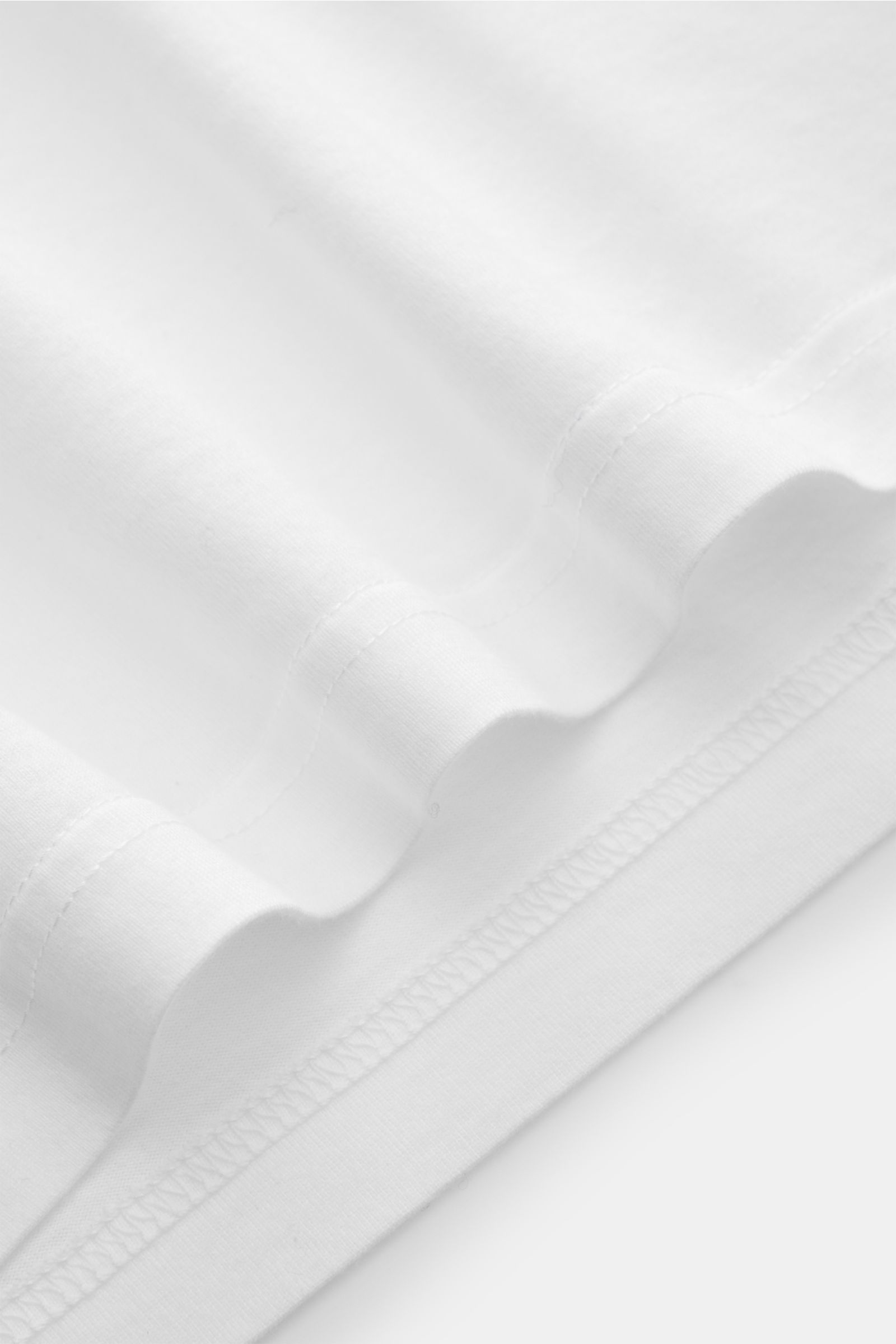 Nahaufnahme des weißen Fedeli Jersey Longsleeve-Poloshirts, die den sanften, seidigen Griff und die feine Jersey-Struktur aus nachhaltiger Giza-Baumwolle zeigt.