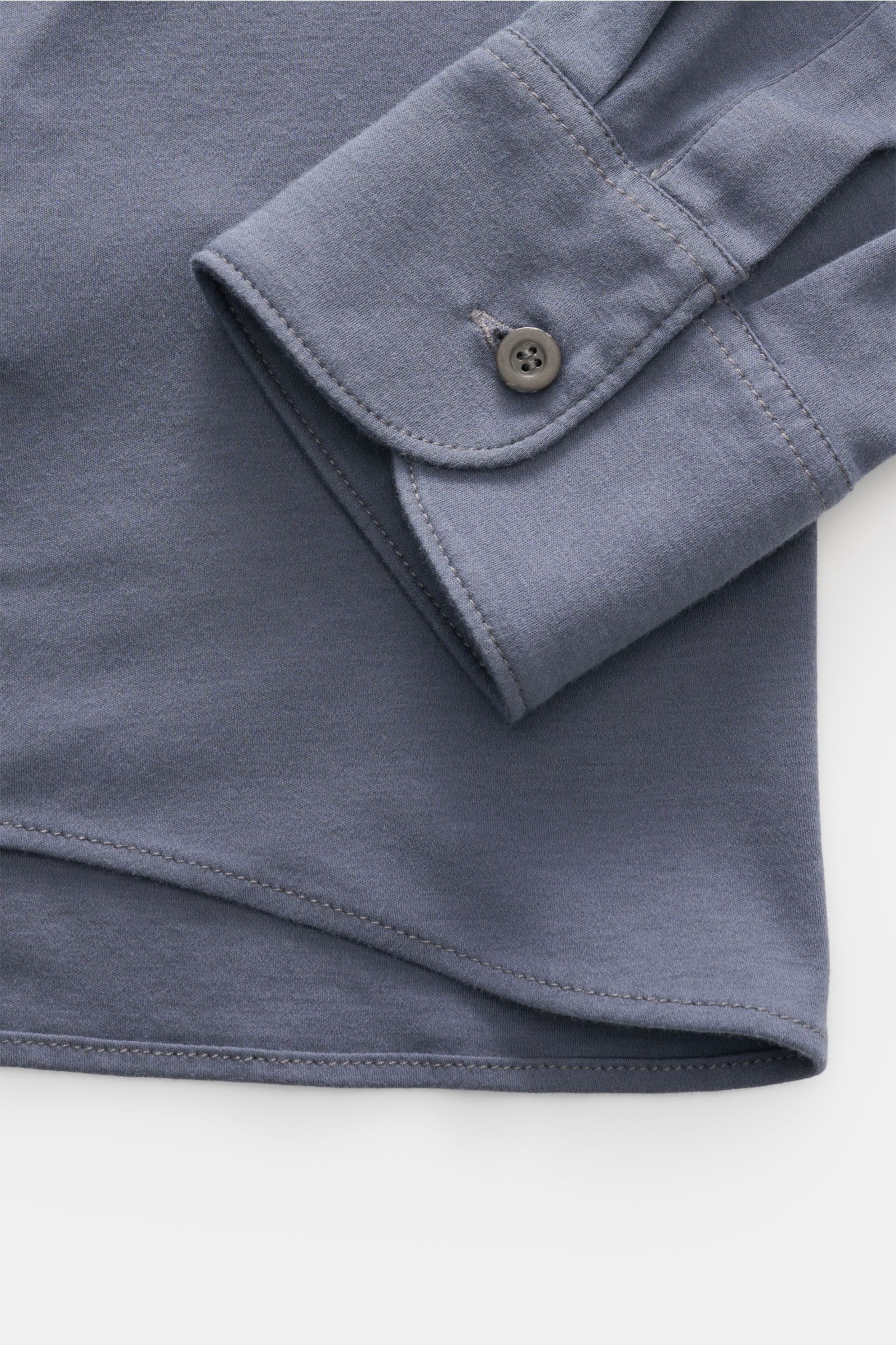 Nahaufnahme des graublauen Piacenza 1733 Jersey-Hemds mit schmalem Kragen, feinem Strickbild, klassischer Sportmanschette und glatter Knopfleiste, fotografiert von oben, zeigt den sehr weichen Griff aus reiner Baumwolle im Slim Fit.