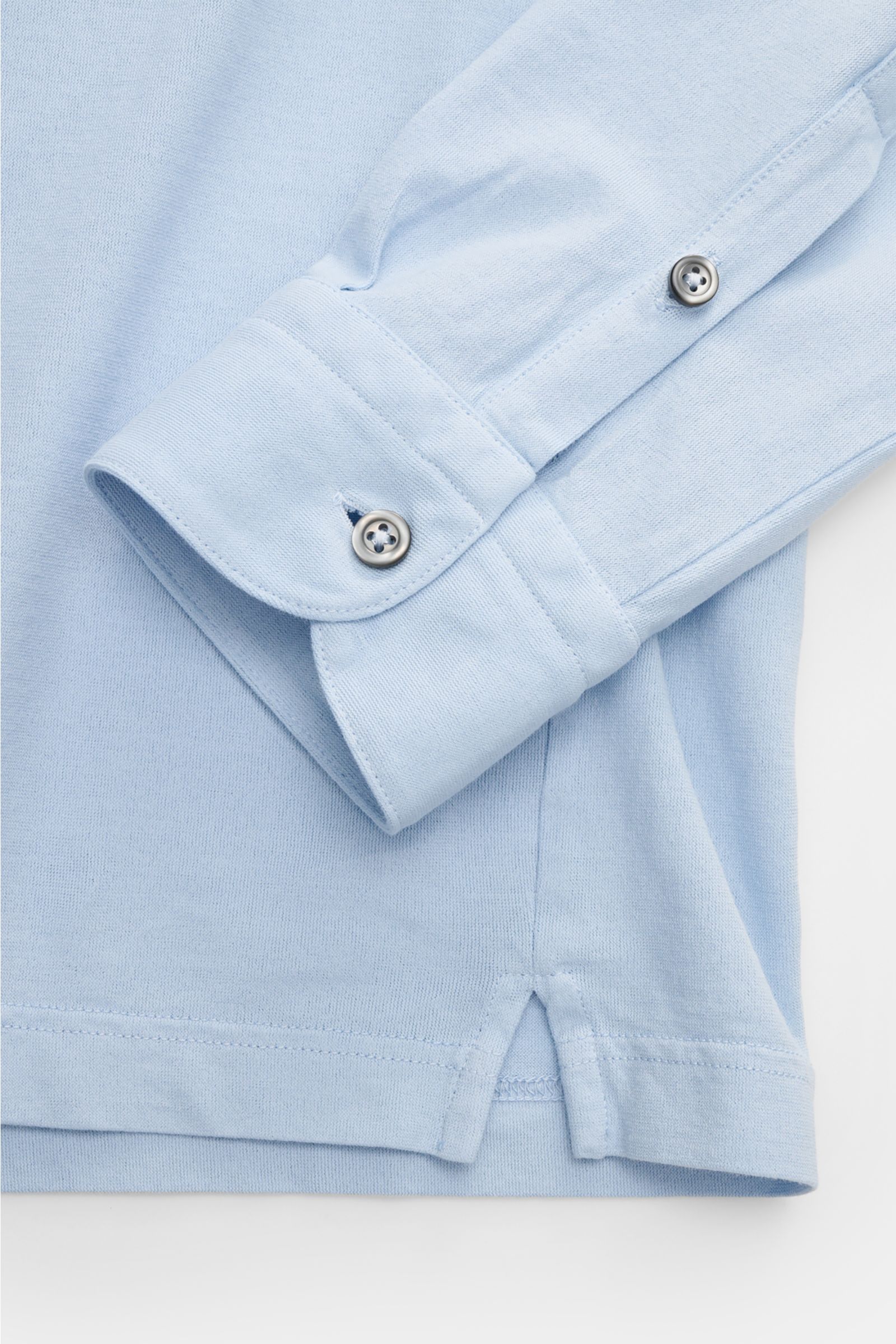 Close-up front-side view of the light blue Gran Sasso Jersey Longsleeve-Poloshirt hellblau, showing cotton jersey fabric, slim fit, shark collar, smooth three-button placket, classic sport cuffs, and side hem slits. Sportiv in die neue Saison: BRAUN HAMBU