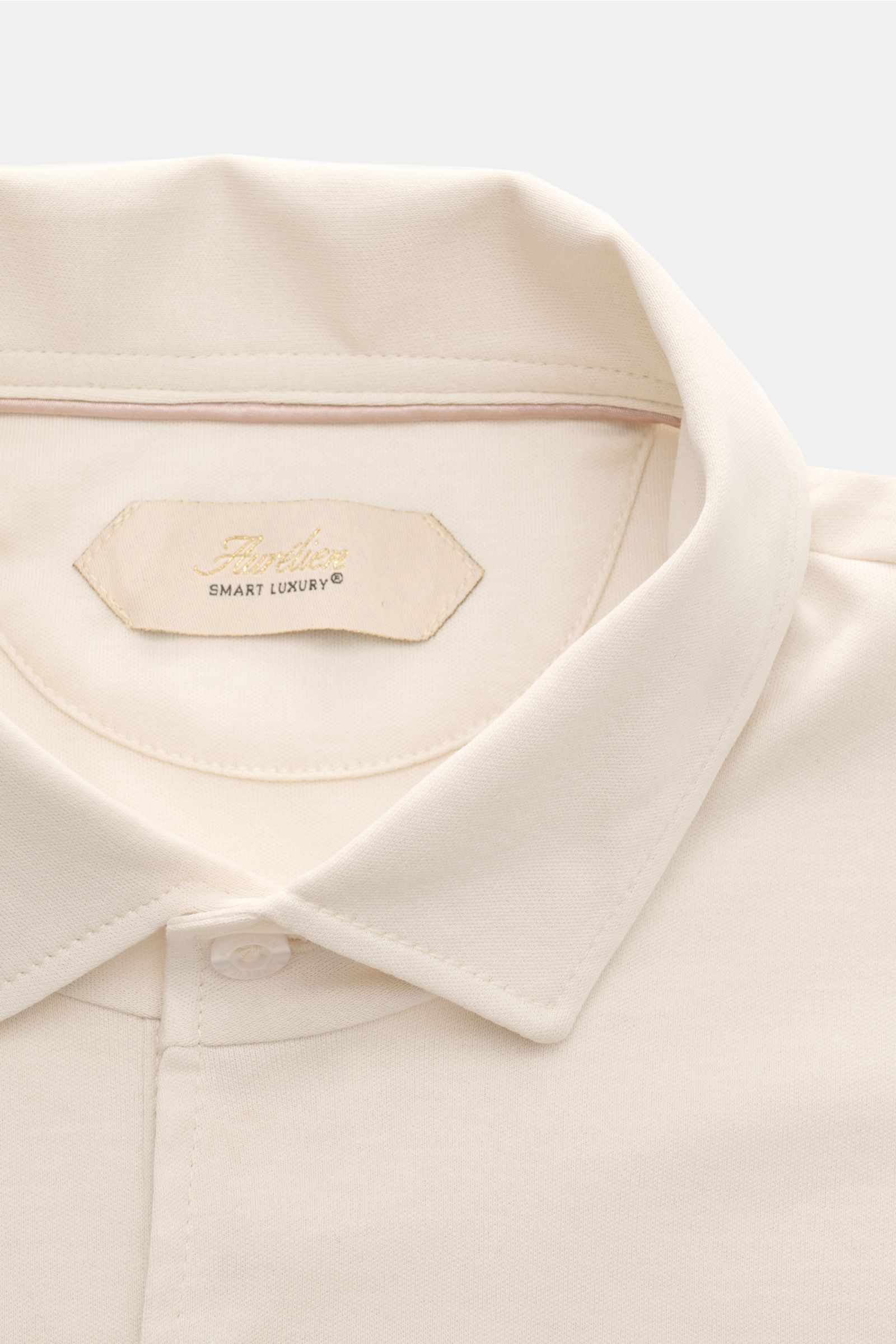 Close-up front view of the Aurélien Jersey Longsleeve-Poloshirt sand, showcasing the soft Egyptian cotton jersey, slim fit, classic polo collar, three-button placket, and subtle logo stitching on the back.

Das vielseitig einsetzbare Longsleeve-Poloshi