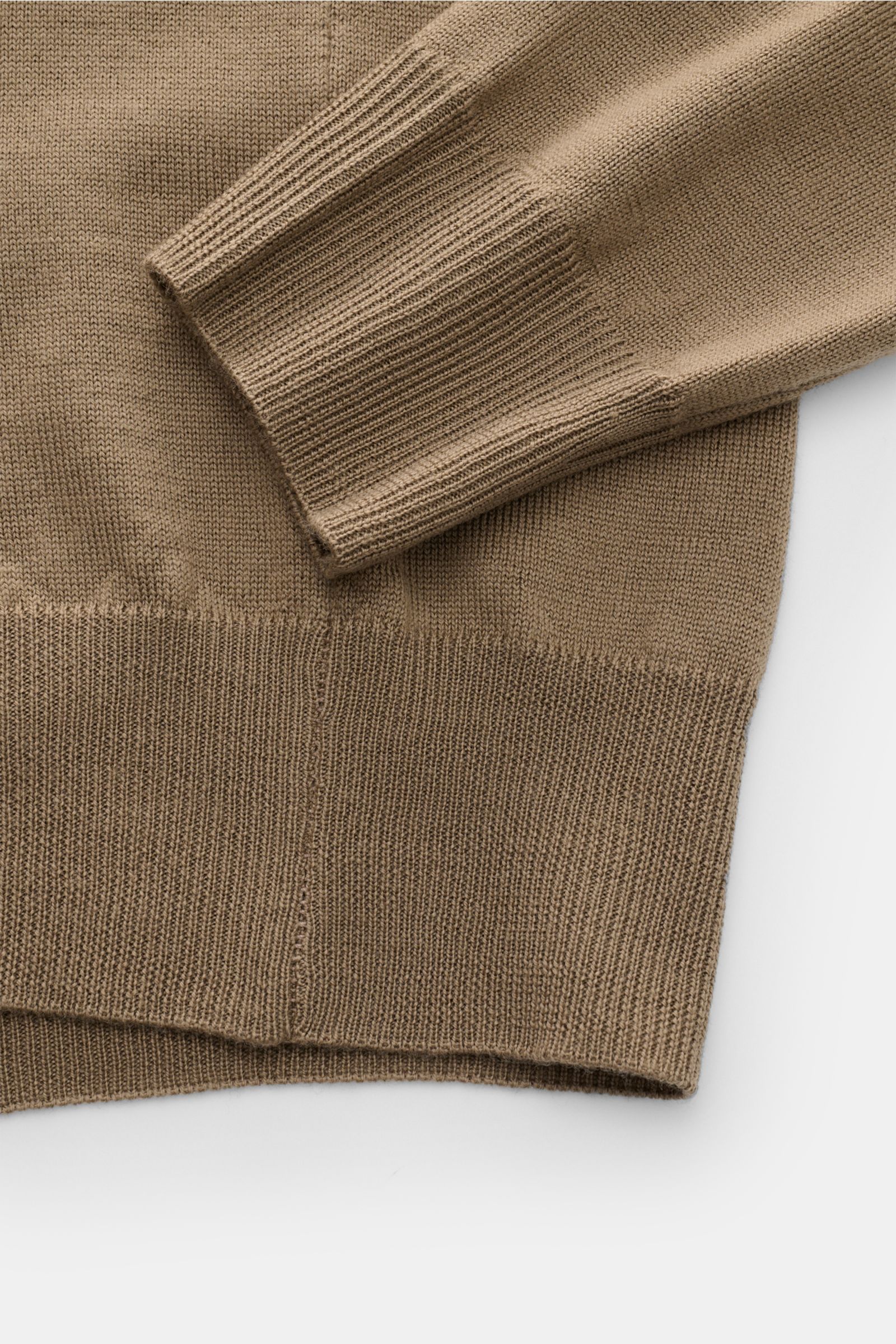 Nahaufnahme des taupefarbenen Aurélien Merino Strickpolo, Perspektive auf Ärmel und Saum mit feinem Strickbild, Slim Fit, offener Polokragen, weicher Merinowolle, Rippbündchen.