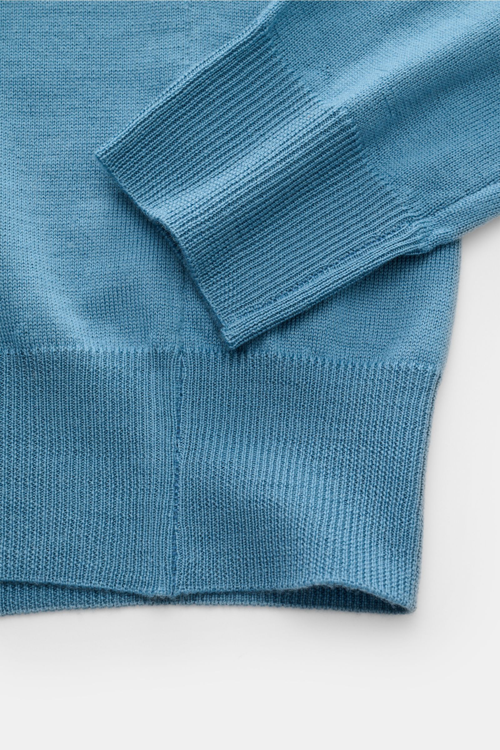 Nahaufnahme des Aurélien Merino Strickpolo blau, fotografiert von unten, zeigt weiche Merinowolle, Slim Fit, offene Kragenleiste und Rippbündchen.