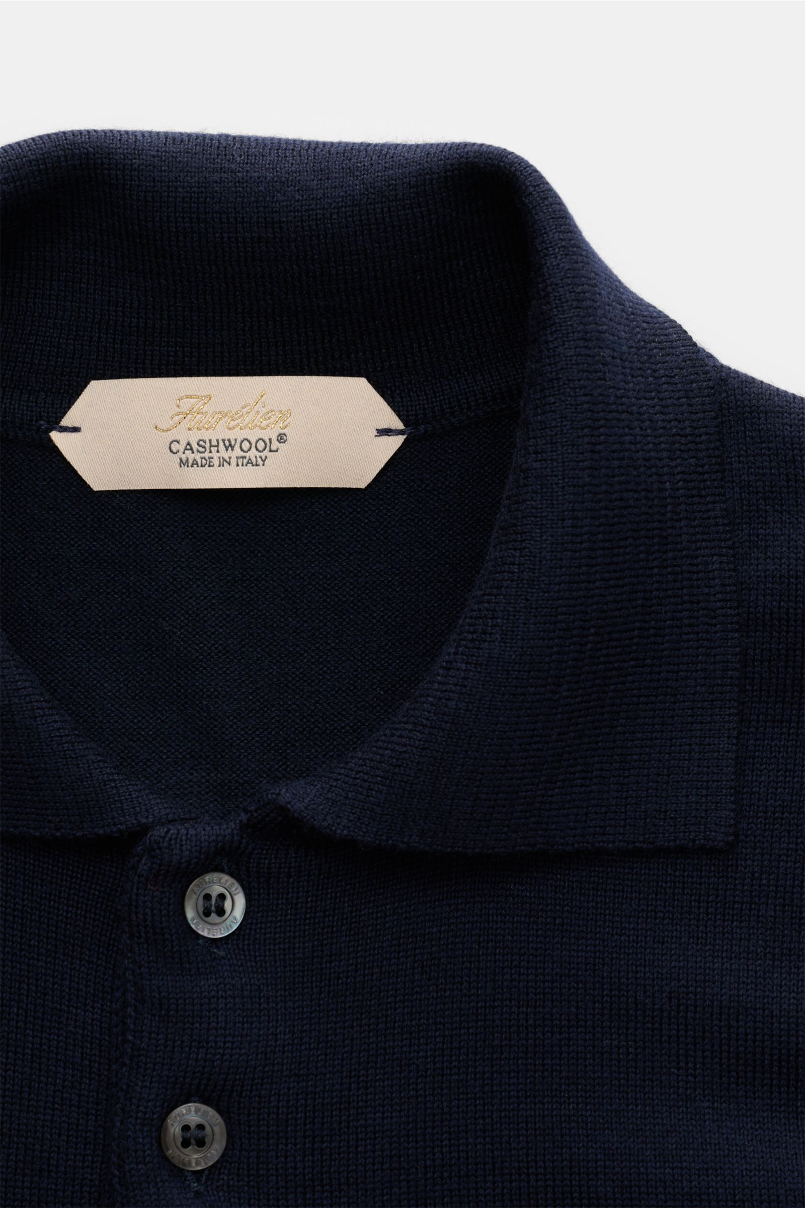 Close-up front view of the Aurélien Merino knit polo navy showing its fine knit, signature polo collar, and buttons with a label stating Cashwool® made in Italy. Ideal for sophisticated casual looks: This knit polo has been made in Italy by AURÉLIEN from 