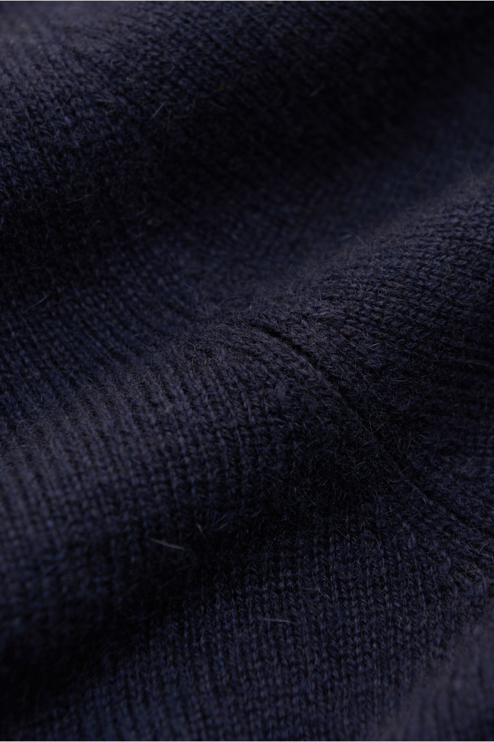 Close-up detail of the navy fabric texture of the von Braun Cashmere Strickpolo, photographed from a top-down perspective. Elegantes Basic für die kalte Jahreszeit: Das VON BRAUN Strickpolo ist eine edle Alternative zum Pullover - gefertigt aus reinem 