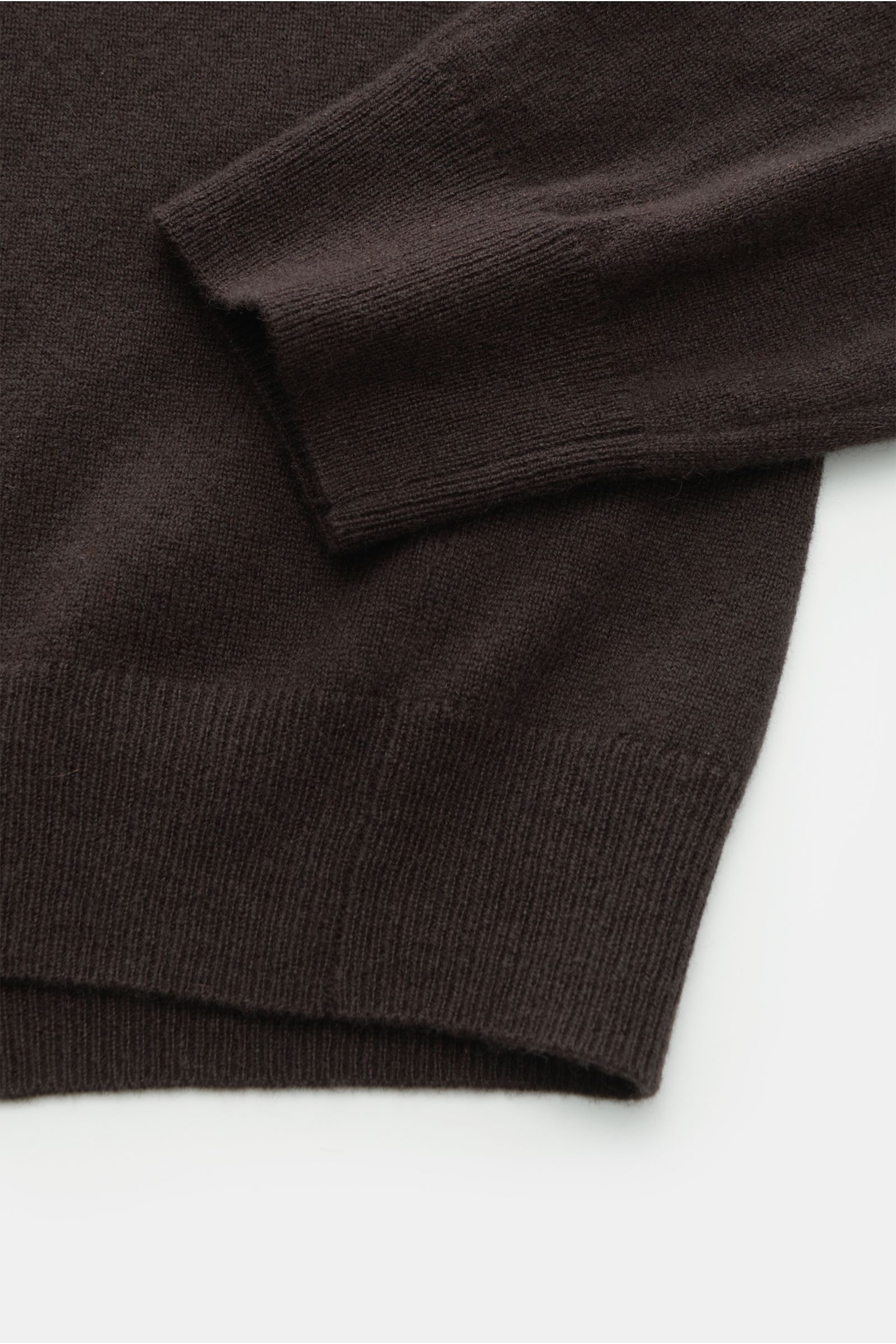 Close-up top-down view of the von Braun Cashmere knit polo dark brown sleeve and hem, showcasing fine knit and elasticated ribbed bands. Elegant basic for the cold season: This VON BRAUN knit polo is an elegant alternative to a jumper – made from pure cas