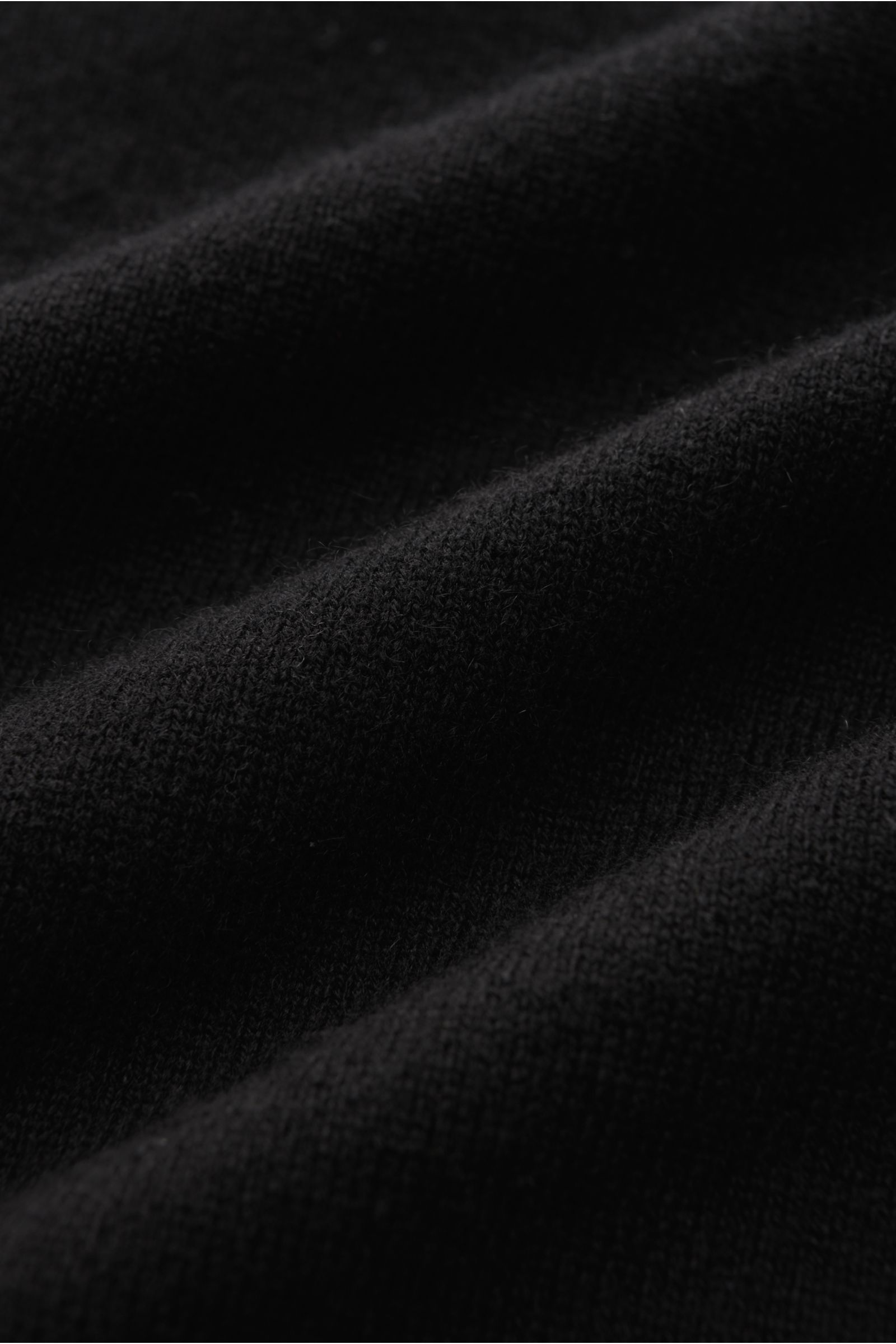 Close-up front view of von Braun Cashmere knit polo black fabric, showing its fine knit, pure cashmere softness, and warmth.