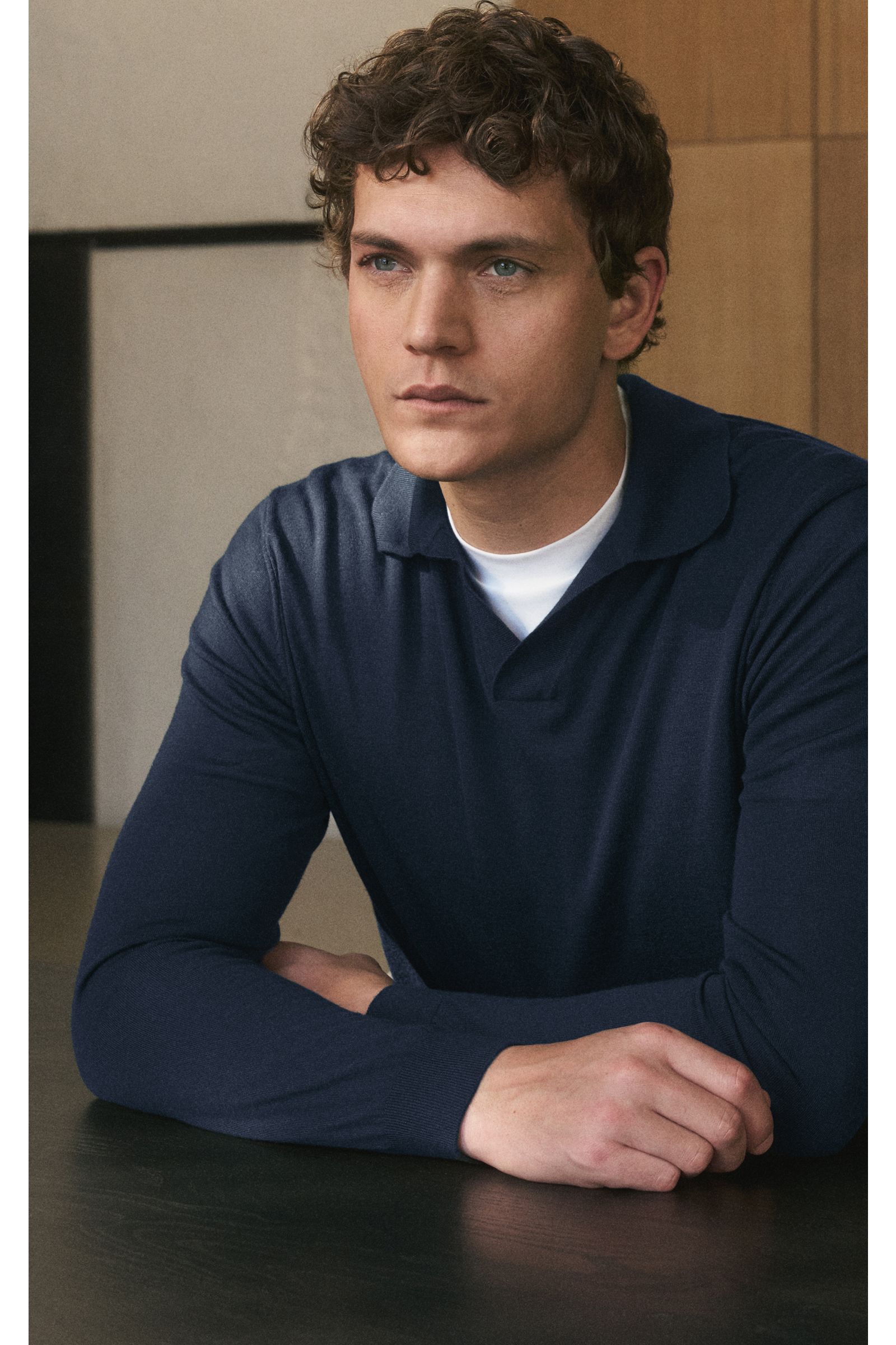 Mann in seitlicher Nahaufnahme trägt von Braun Merino Strickpolo navy aus reiner Merinowolle mit offenem Kragen, Regular Fit, elastischen Rippbündchen.