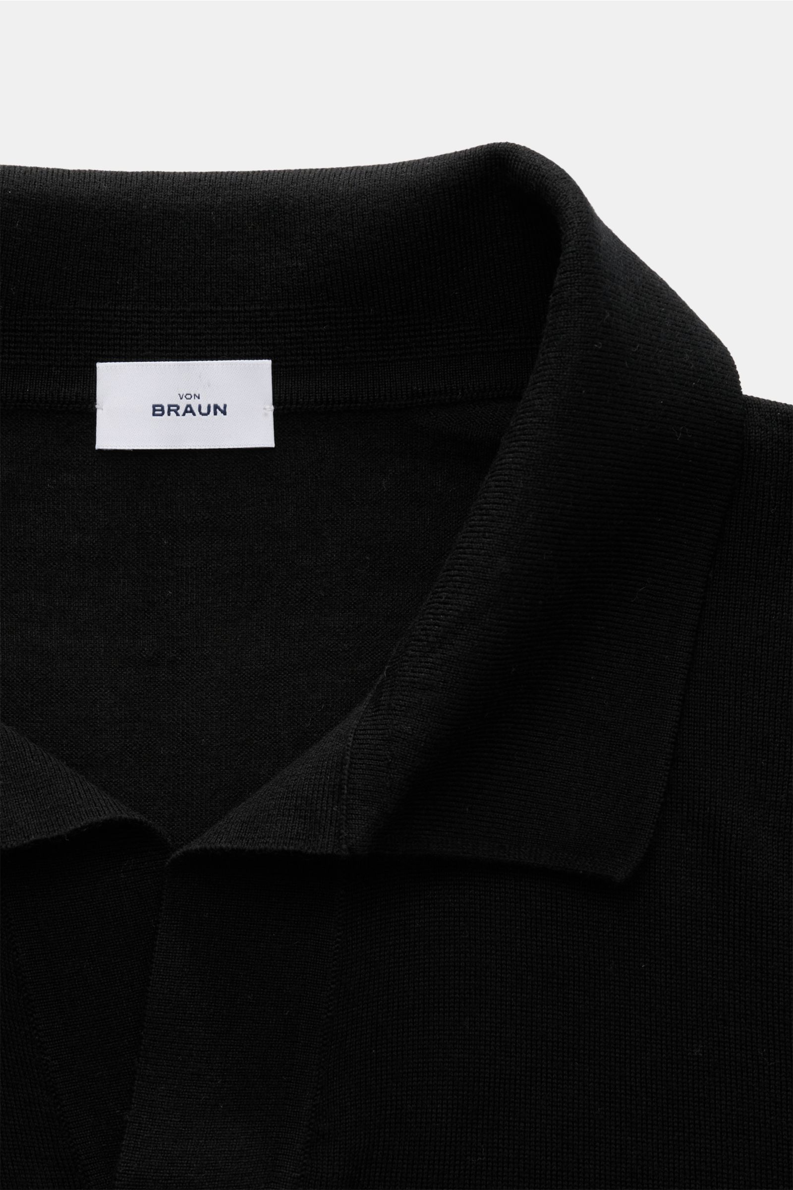 Nahaufnahme von von Braun Merino Strickpolo schwarz mit offenem Polokragen, feinem Strickbild und elastischen Rippbündchen, aus reiner Merinowolle.