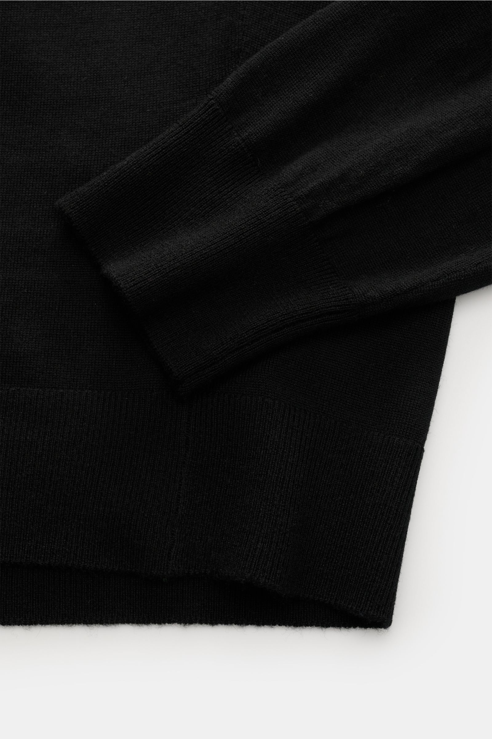 von Braun Merino Strickpolo schwarz, Detailaufnahme von Ärmel und Bund, feines Strickbild, weicher Griff, elastische Rippbündchen, Regular Fit, offene Kragenleiste.