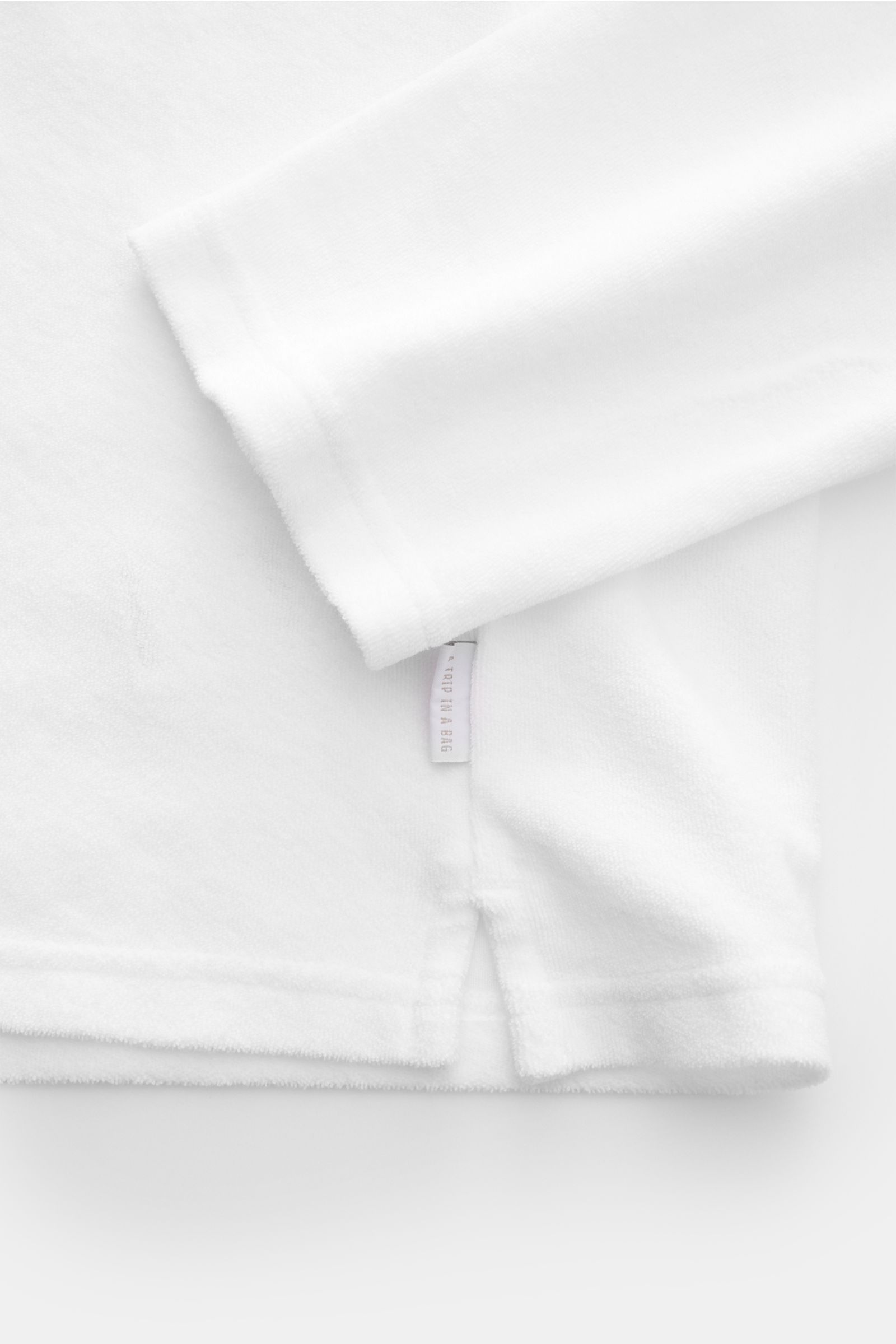 Weißes 04651/ A trip in a bag Frottee Longsleeve-Poloshirt 'Terry Johnny' aus Baumwoll-Frottee, weicher Griff, Regular Fit, seitliche Saumschlitze, Detail von unten schräg.