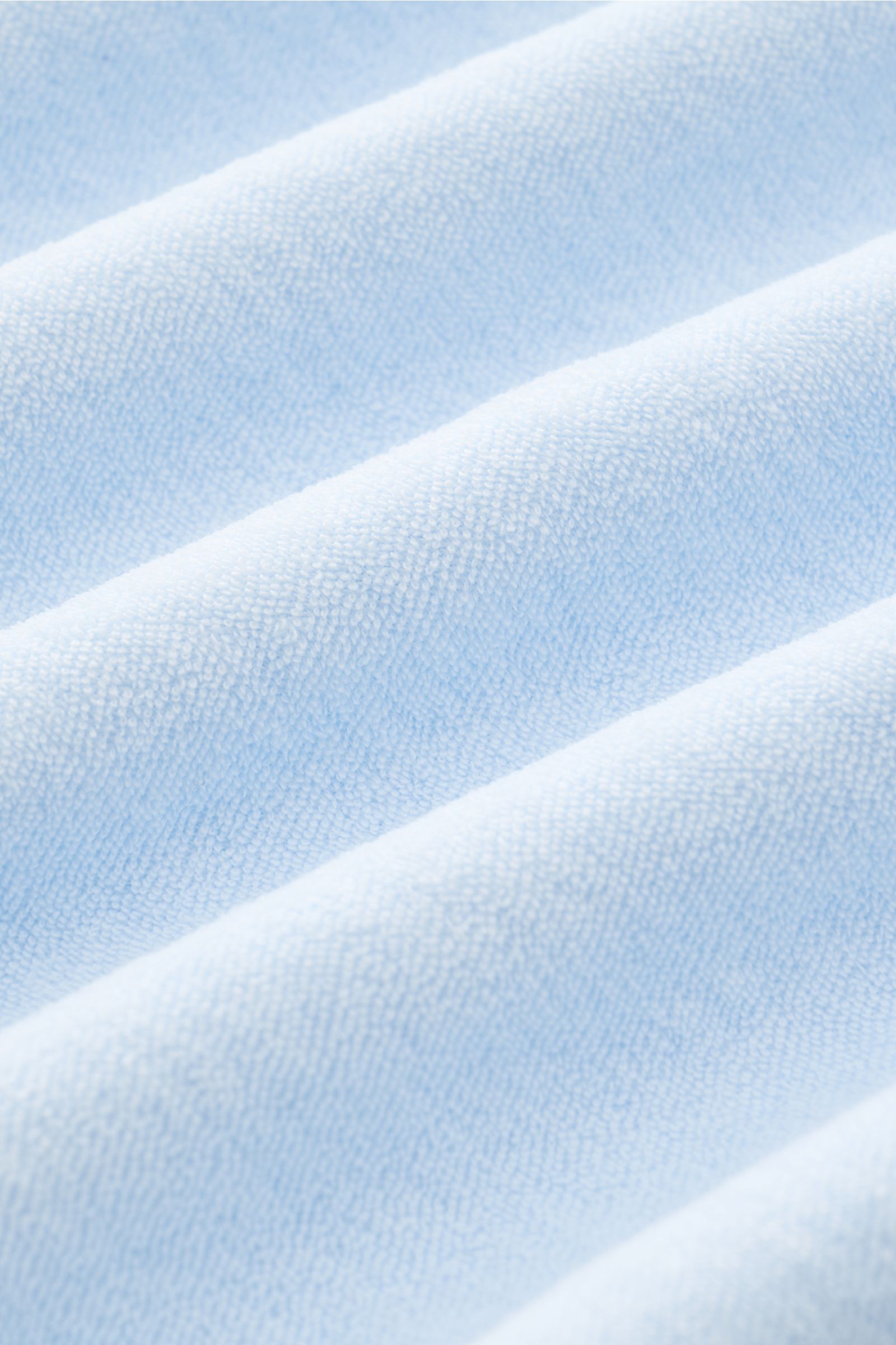 Nahaufnahme des weichen Baumwoll-Frottee-Stoffs des 04651/ A trip in a bag Frottee Longsleeve-Poloshirt 'Terry Johnny' pastellblau mit feiner Struktur.