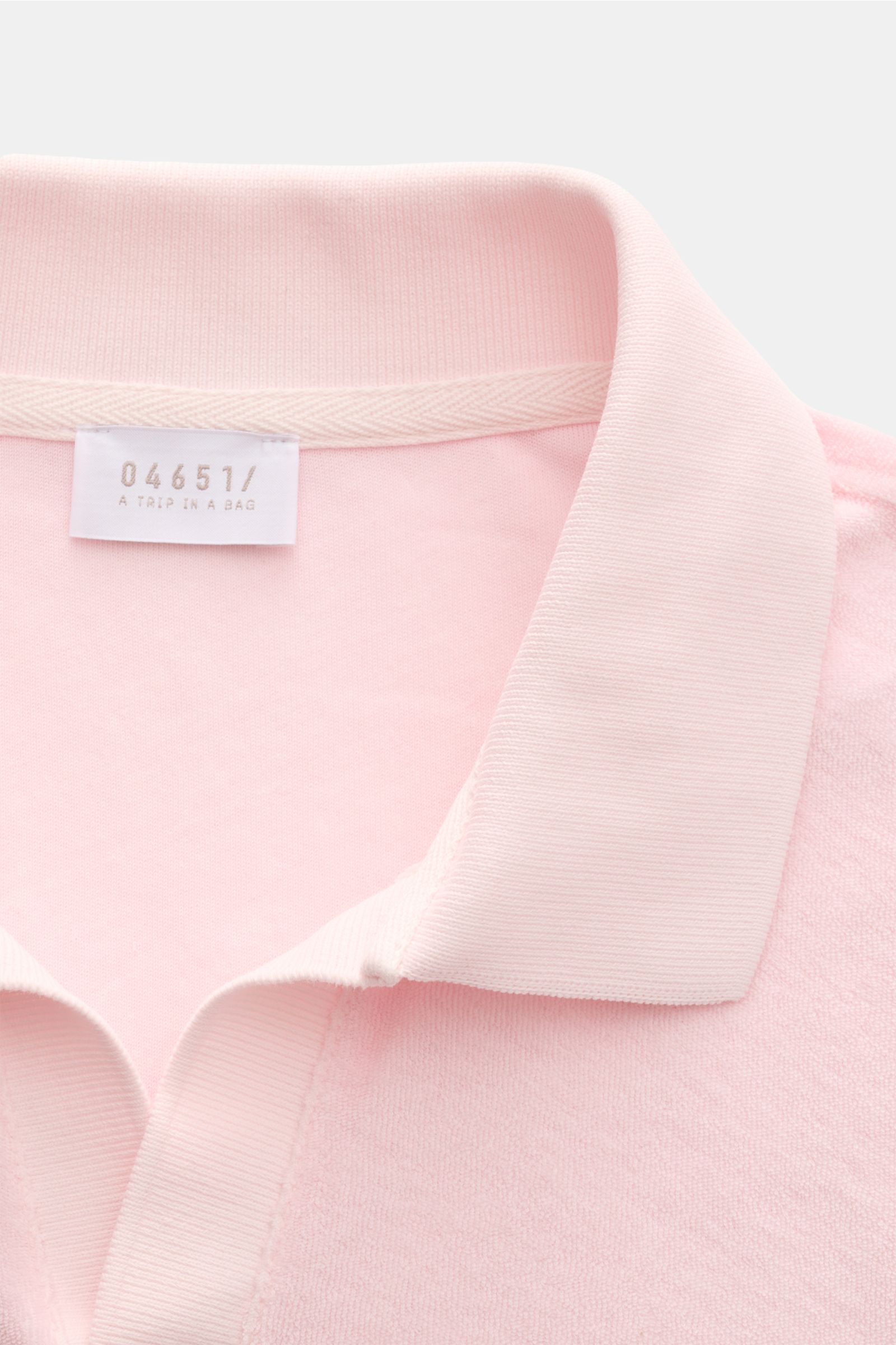 Nahaufnahme des Kragens und oberen Bereichs des 04651/ A trip in a bag Frottee Longsleeve-Poloshirt 'Terry Johnny' rosé aus weichem Baumwoll-Frottee mit klassischem Polokragen, offener Kragenleiste und kurzem Saumschlitz, fotografiert von oben.