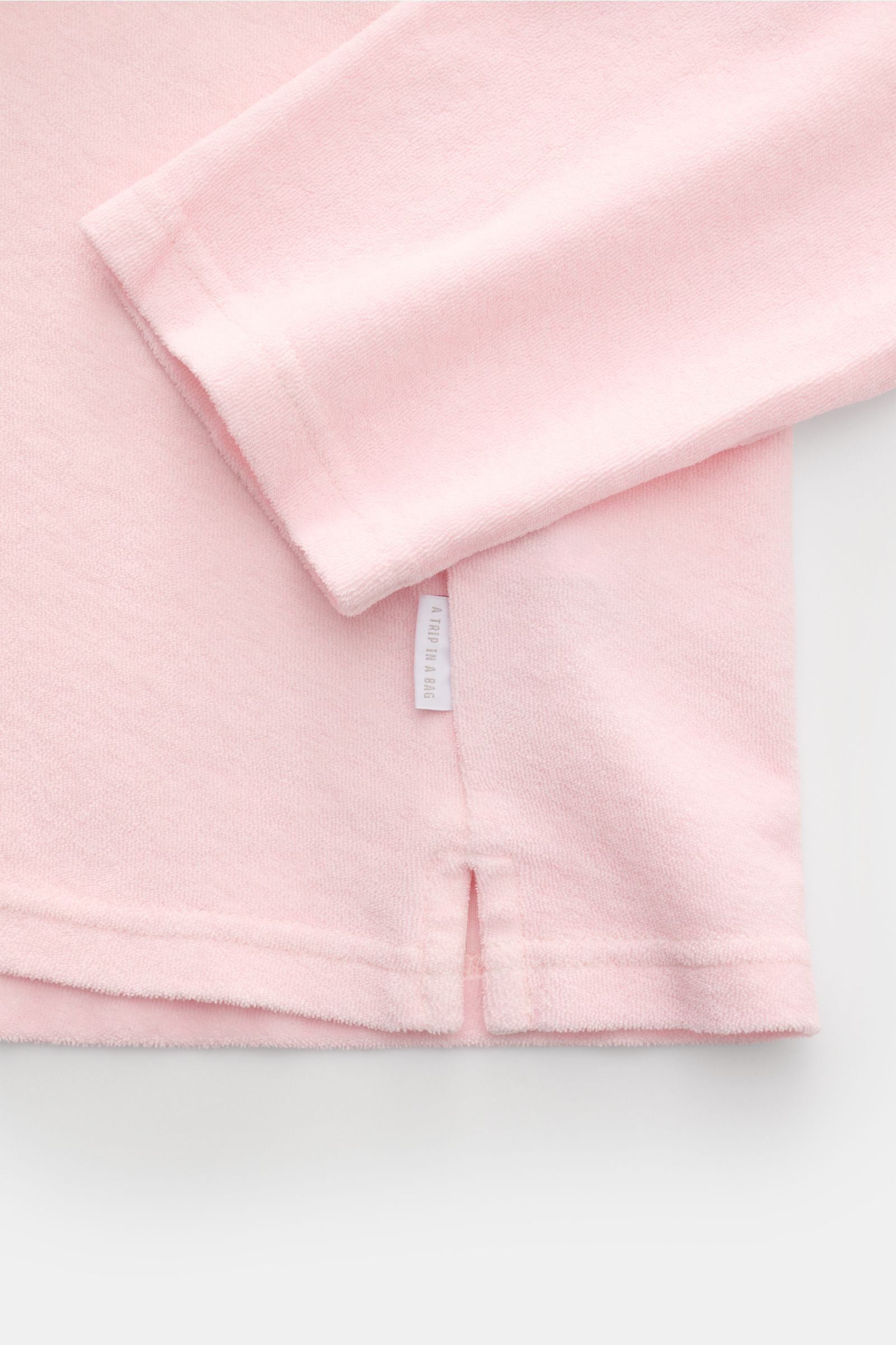 Detailaufnahme aus seitlicher Perspektive des 04651/ A trip in a bag Frottee Longsleeve-Poloshirt 'Terry Johnny' rosé mit kurzen Saumschlitzen aus weichem Baumwoll-Frottee.