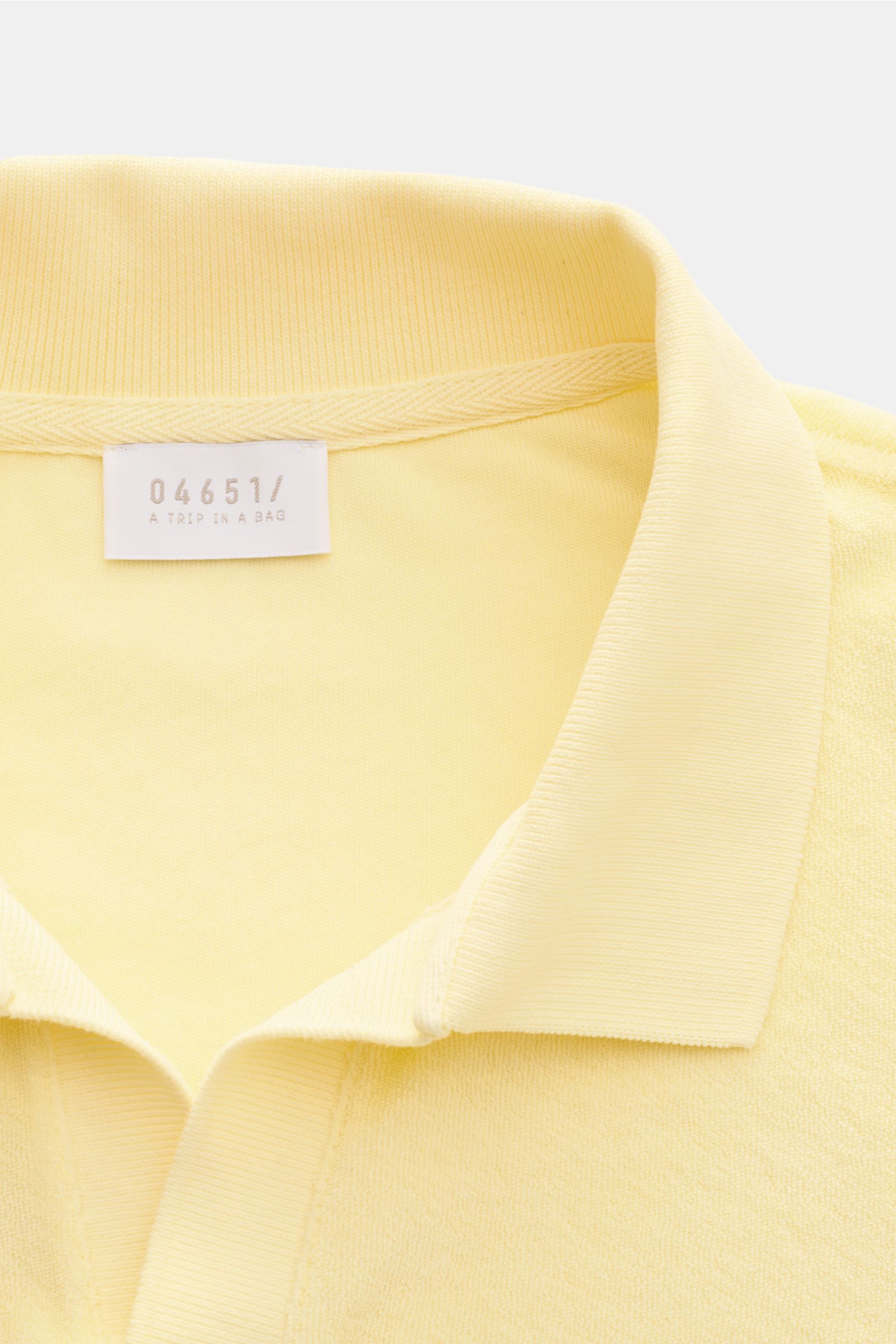 Nahaufnahme aus schräger Perspektive des pastellgelben 04651/ A trip in a bag Frottee Longsleeve-Poloshirt 'Terry Johnny' mit klassischem Polokragen aus reiner Baumwolle, weichem Griff, Regular Fit, offener Kragenleiste und kurzen Saumschlitzen – Urlaubsg