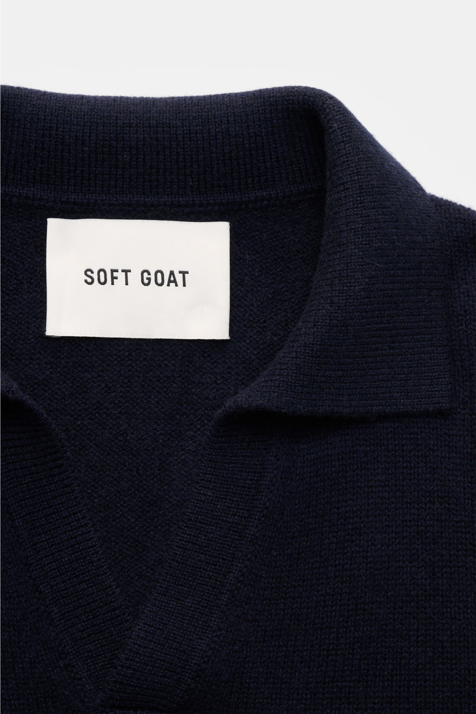 Nahaufnahme des Soft Goat Cashmere Strickpolo navy mit offenem Kragen und mittelfeinem Strickbild, von oben fotografiert.
