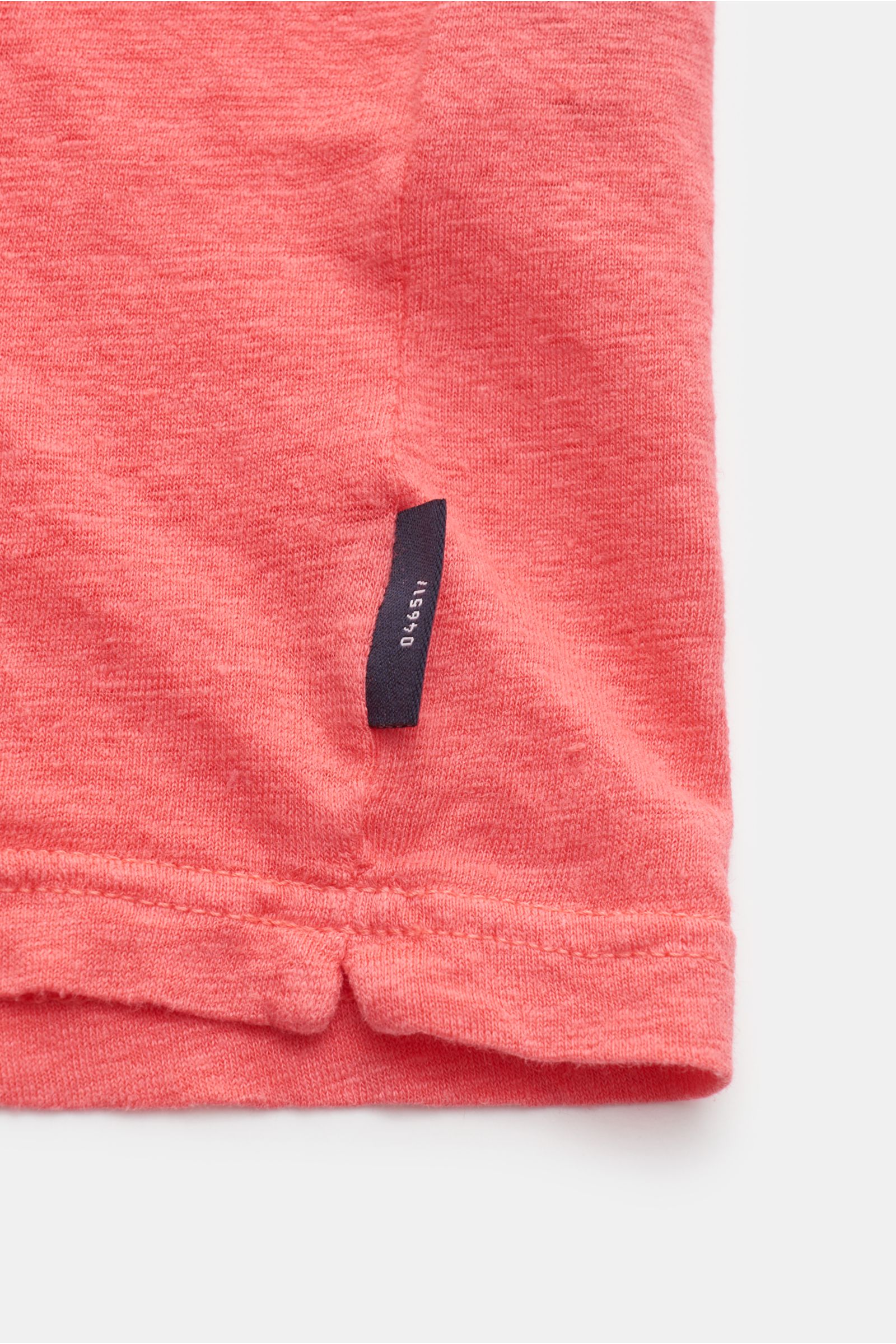 04651/ A trip in a bag Leinen Rundhals-T-Shirt koralle, Detailaufnahme rechts unten mit kurzem Saumschlitz und kleinem Weblabel aus elastischem, garment dyed Leinen.