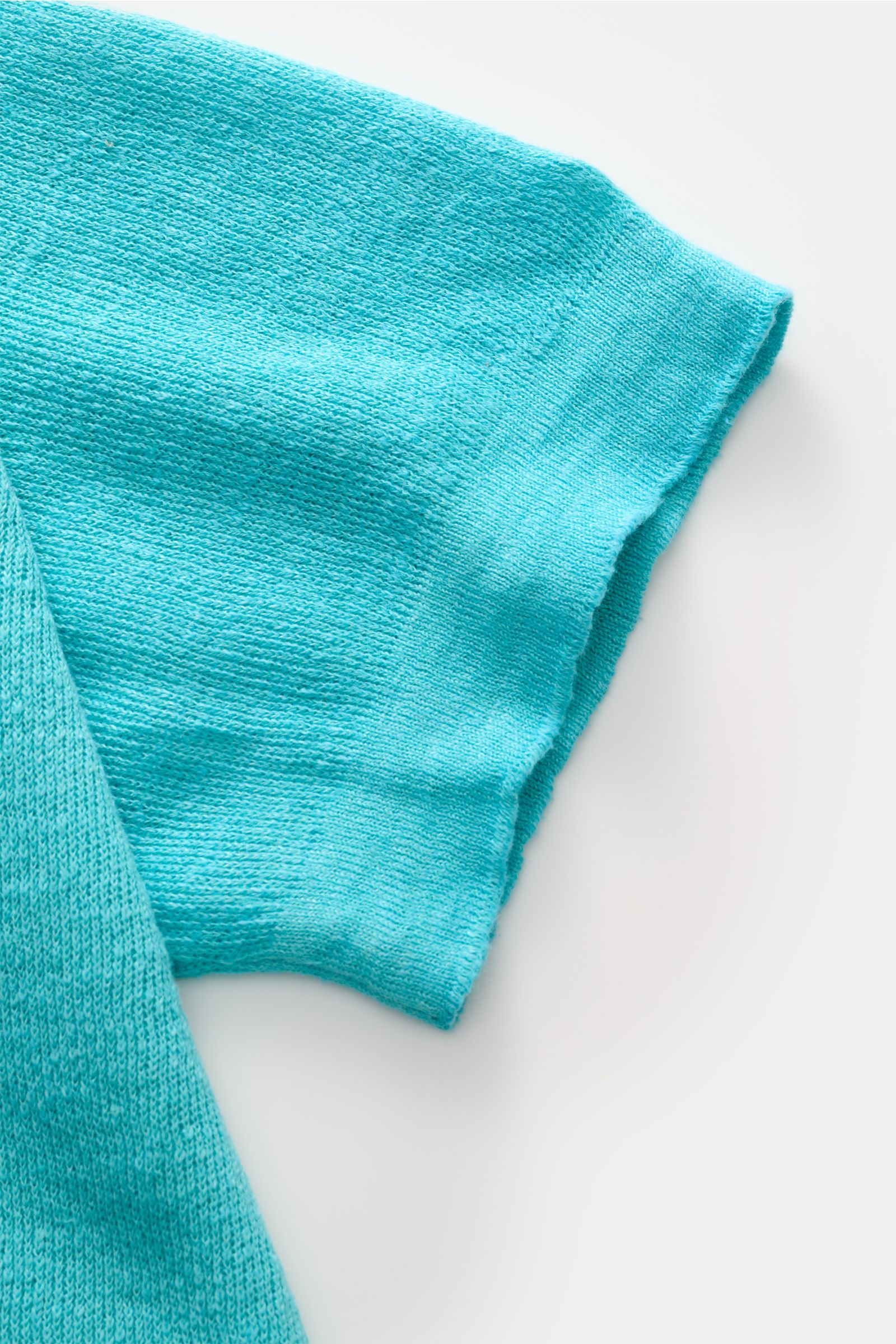 Ausschnitt eines türkisfarbenen 04651/ A trip in a bag Polo-Shirts, Ärmel aus seitlicher Perspektive fotografiert.