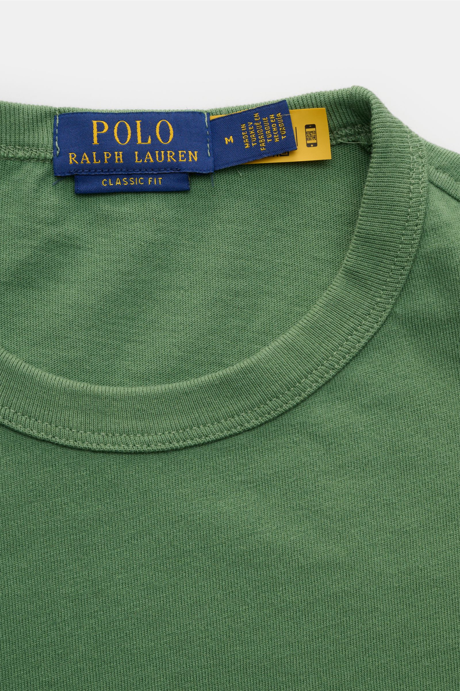 Close-up front view of Polo Ralph Lauren Rundhals-T-Shirt grün showing green fabric and blue label. Jersey aus reiner Baumwolle, weiche Qualität, Regular Fit, Rundhalsausschnitt, labeltypisches Logo-Stitching auf der Brust.