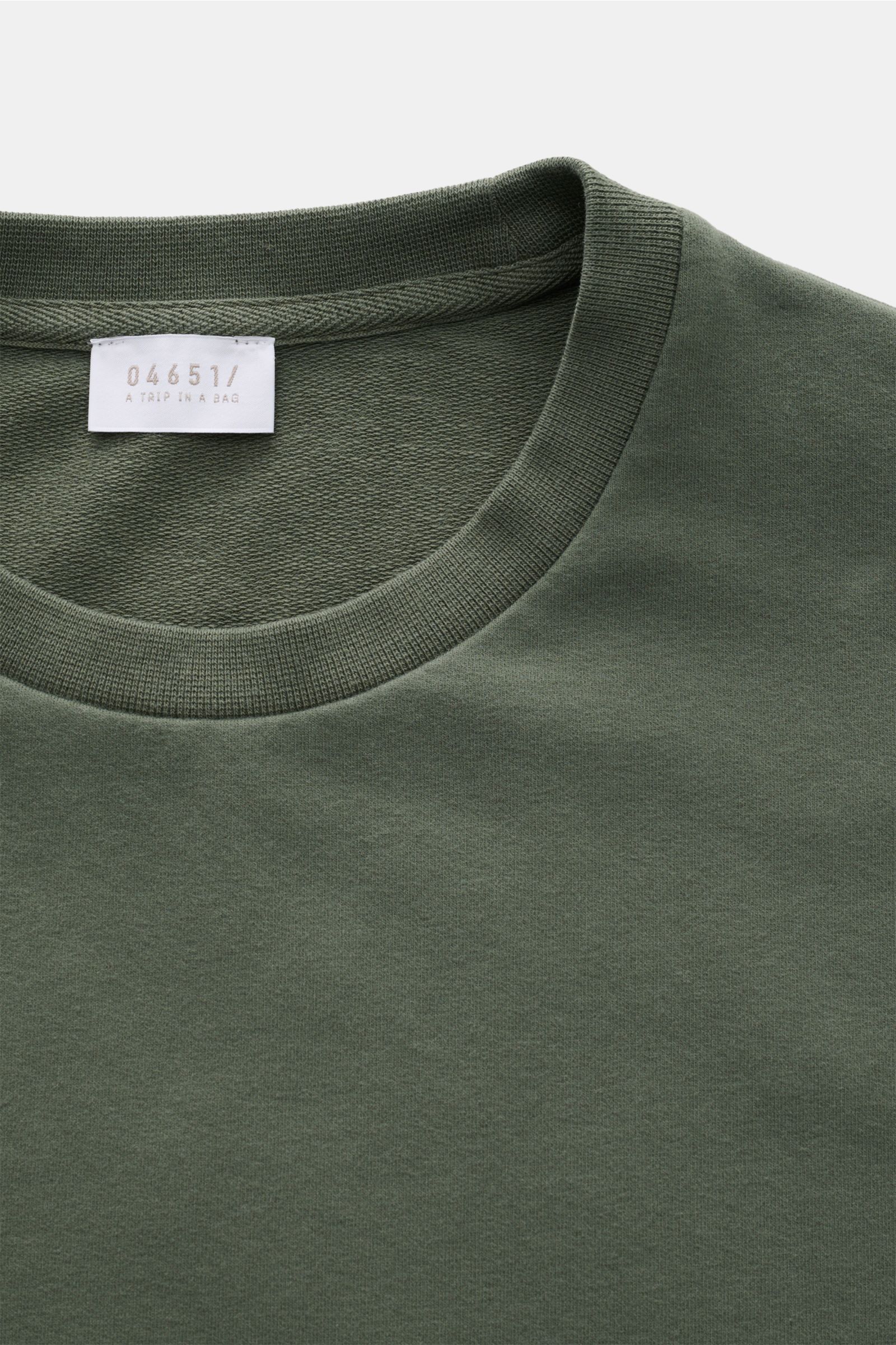 Nahaufnahme des graugrünen 04651/ A trip in a bag Rundhals-T-Shirts 'If Tee' mit weichem, elastischem Baumwoll-Jersey und Weblabel in der Seitennaht.
