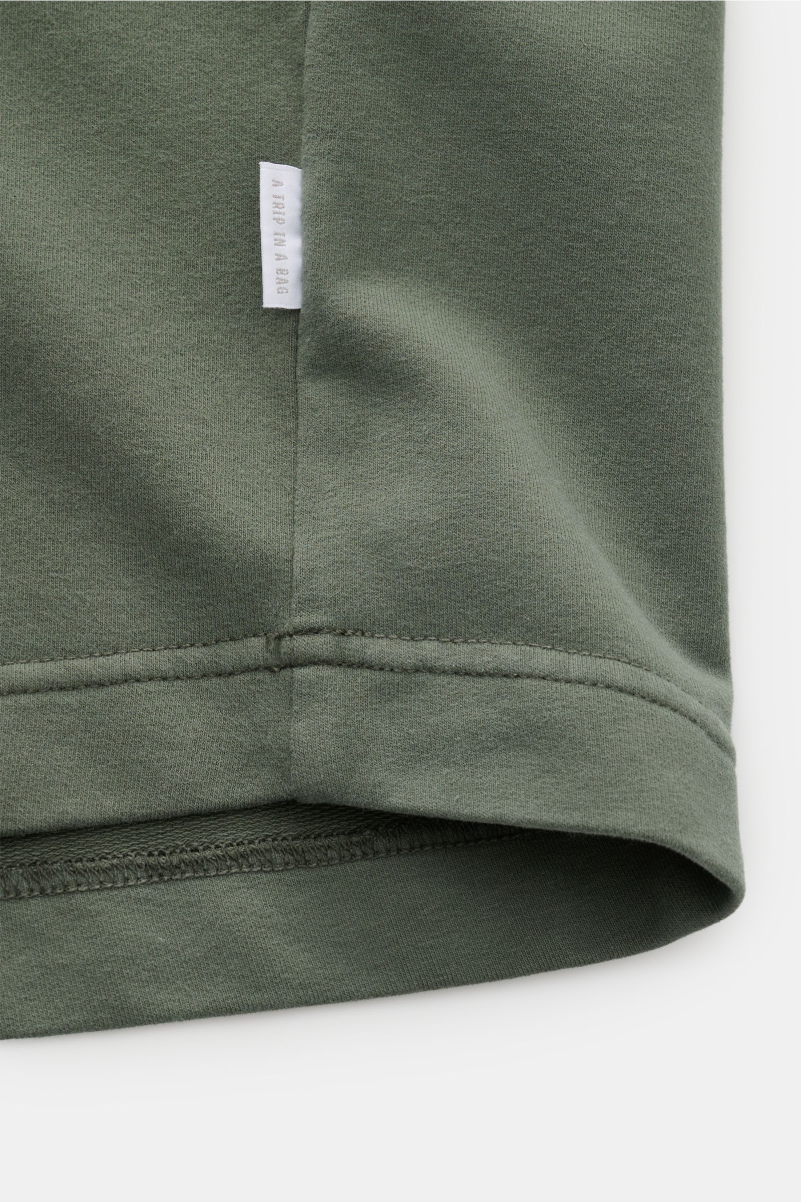 04651/ A trip in a bag Rundhals-T-Shirt 'If Tee' graugrün, Detailansicht Saum und Weblabel, elastische Baumwolle, Oversized Fit, schwerer Stoff.