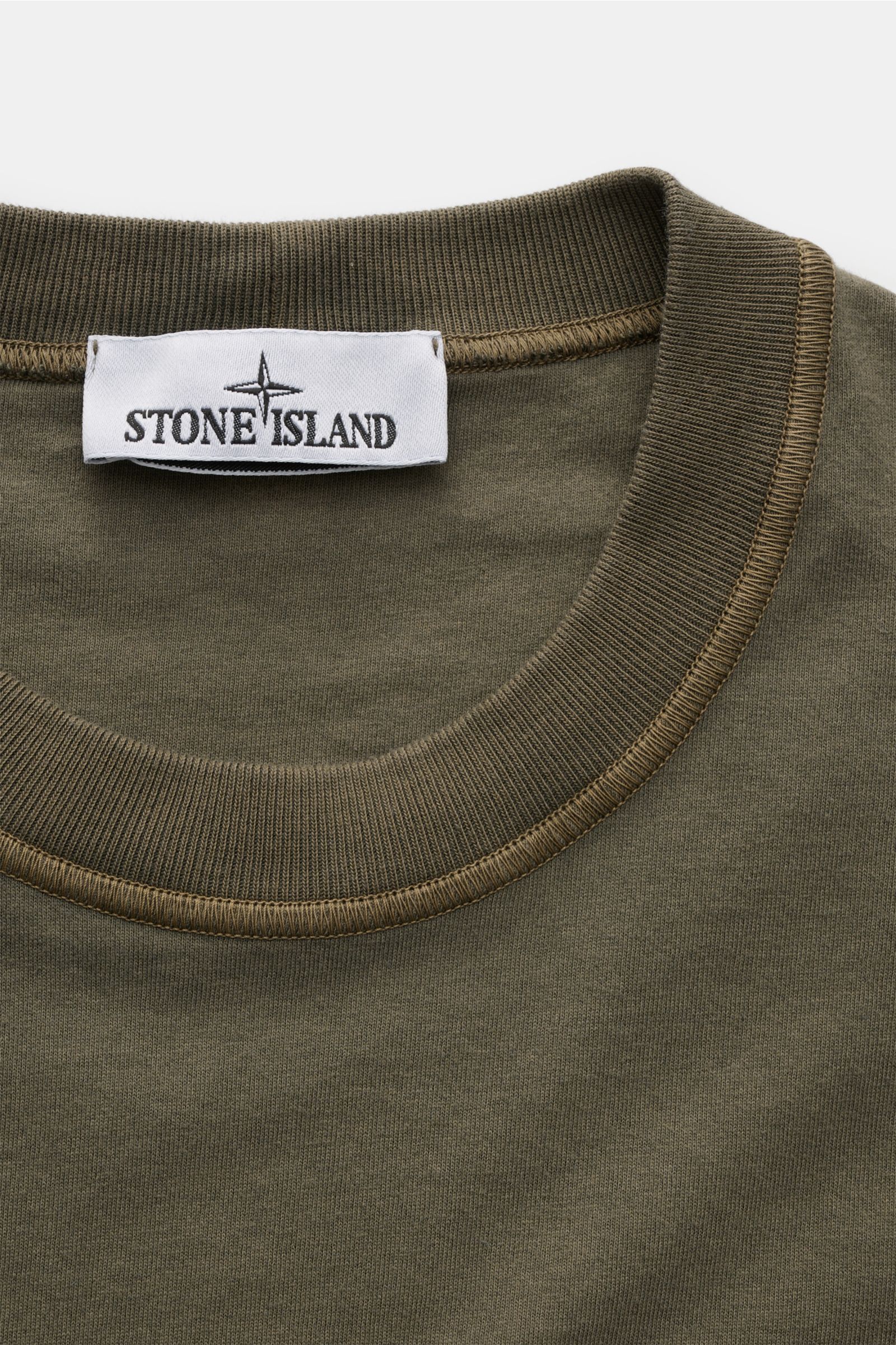 Stone Island Crew neck T-shirt olive shown from a close-up top front perspective, featuring a ribbed crew neck with distinctive overlock seams and a white fabric label. STONE ISLAND delivers an essential basic for your casual wardrobe with this relaxed