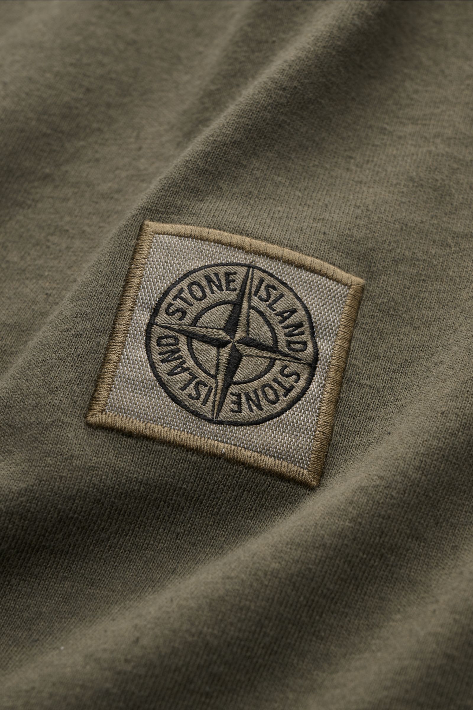 Alt tag (125 characters max): Close-up front view of Stone Island Crew neck T-shirt olive showing the fabric label with compass logo on soft organic cotton.

Description: 
STONE ISLAND delivers an essential basic for your casual wardrobe with this rela