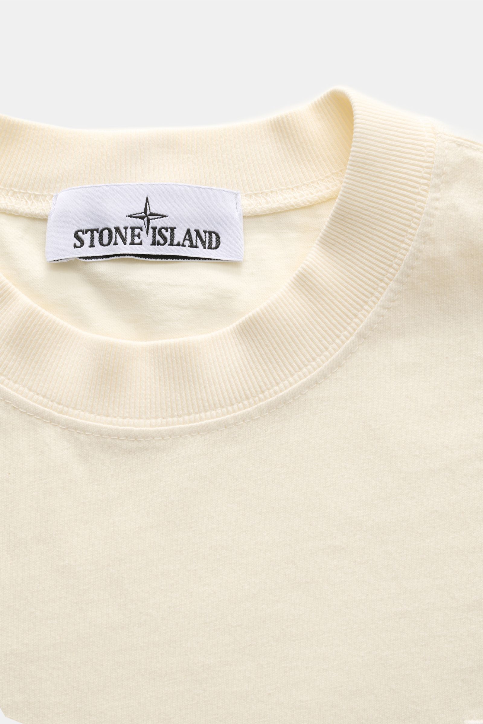 Stone Island Rundhals-T-Shirt creme, Nahaufnahme von Kragen und Label, garment dyed Baumwolle, Regular Fit, Overlock-Nähte, Jersey, Weblabel sichtbar.
