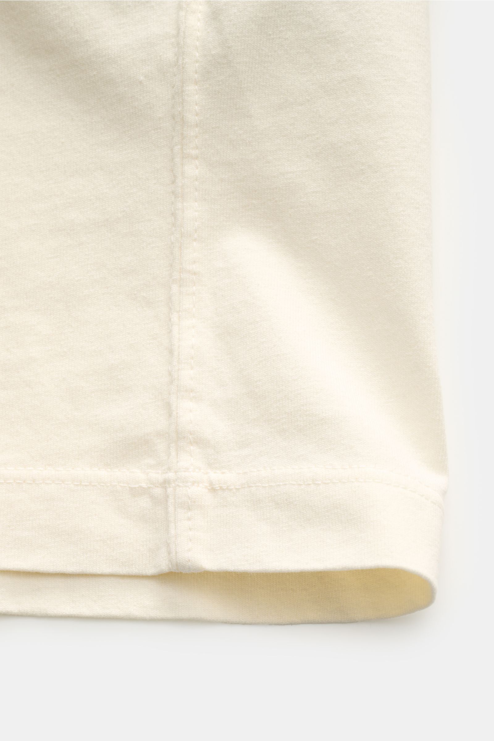 Stone Island Rundhals-T-Shirt creme, Detailaufnahme der unteren Kante mit markanten Overlock-Nähten, garment dyed Baumwolle, Regular Fit.