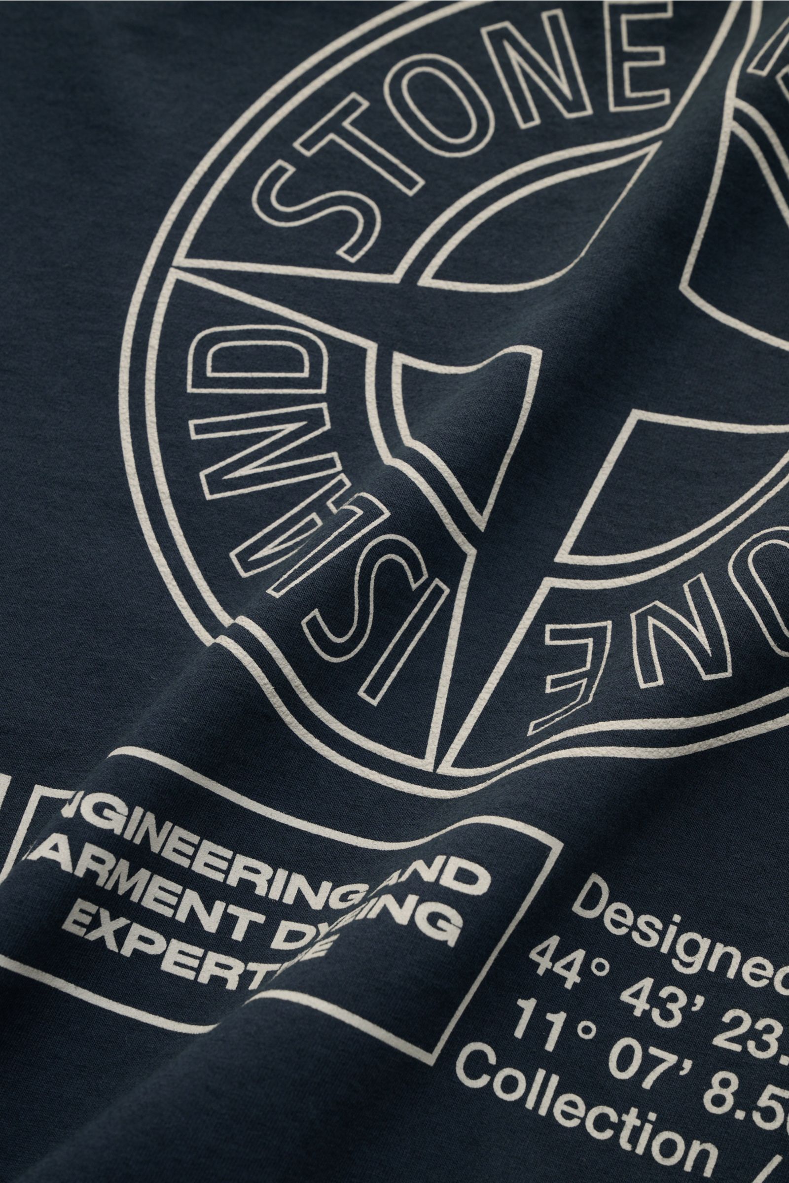 Nahaufnahme des Stone Island Rundhals-T-Shirts 'Industrial Print' dark navy aus garment-dyed-Baumwolle mit weißem STONE ISLAND-Kompass-Print, fotografiert aus frontaler Perspektive.
