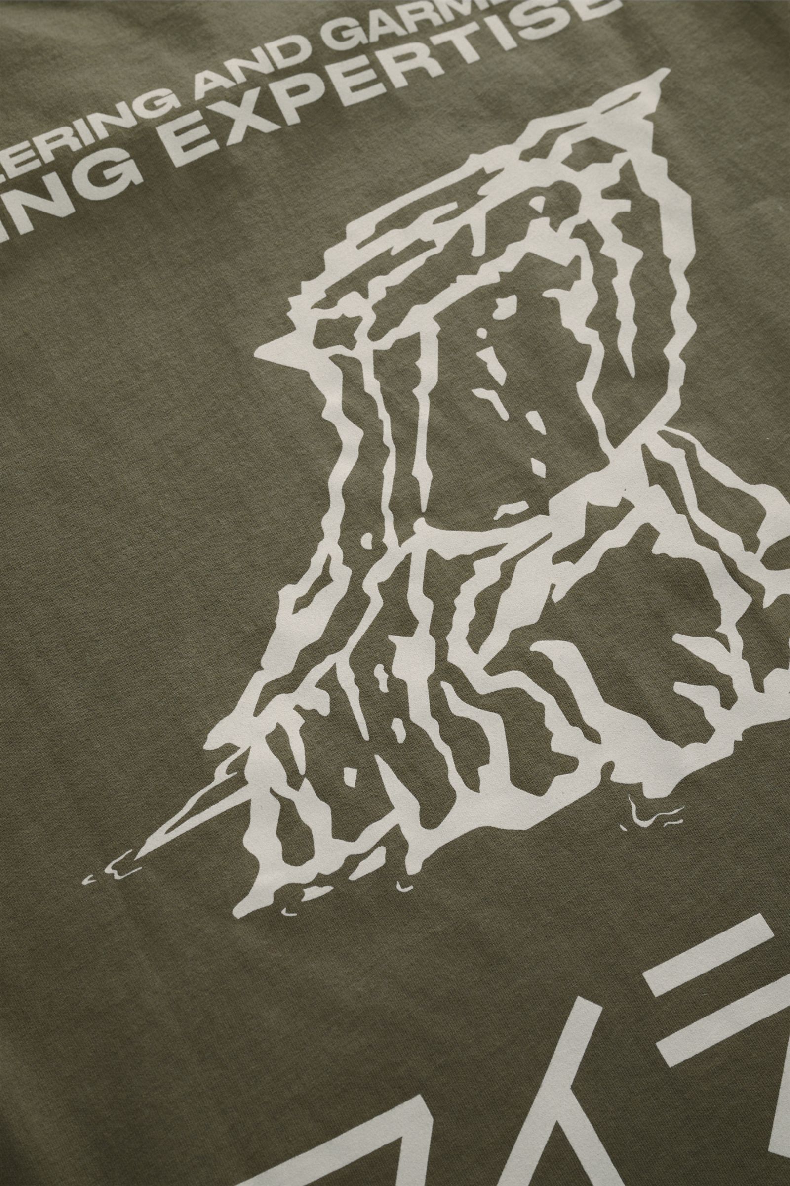 Close-up, angled view of the Stone Island Rundhals-T-Shirt oliv showing a white graphic print on olive fabric. Jersey aus reiner Baumwolle, schwere Qualität, leicht griffige Haptik, garment dyed, Regular Fit, Rundhalsausschnitt, Print auf der Front, plaka