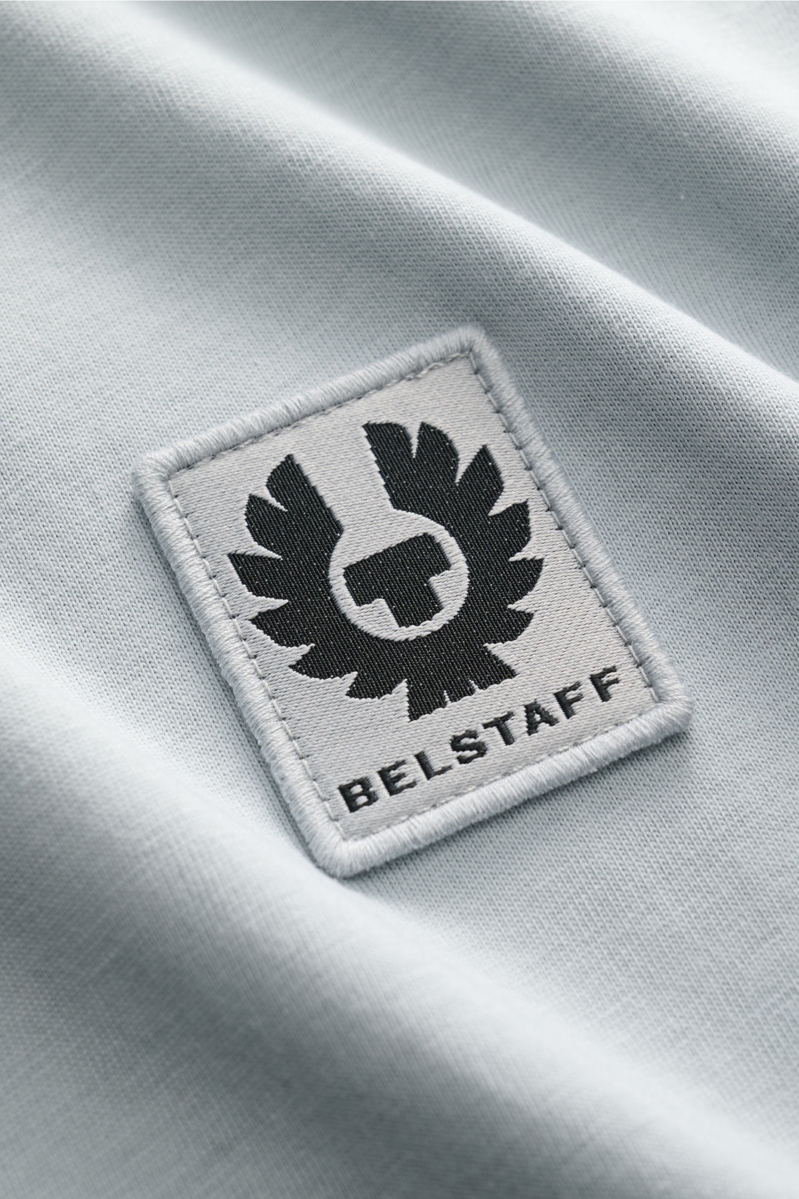 Close-up front view of Belstaff Rundhals-T-Shirt rauchblau showing the tonal BELSTAFF woven label on soft, lightweight cotton jersey fabric.

Dieses T-Shirt von BELSTAFF, gefertigt aus leichtem Baumwoll-Jersey und veredelt mit einem dezenten Ton-in-Ton