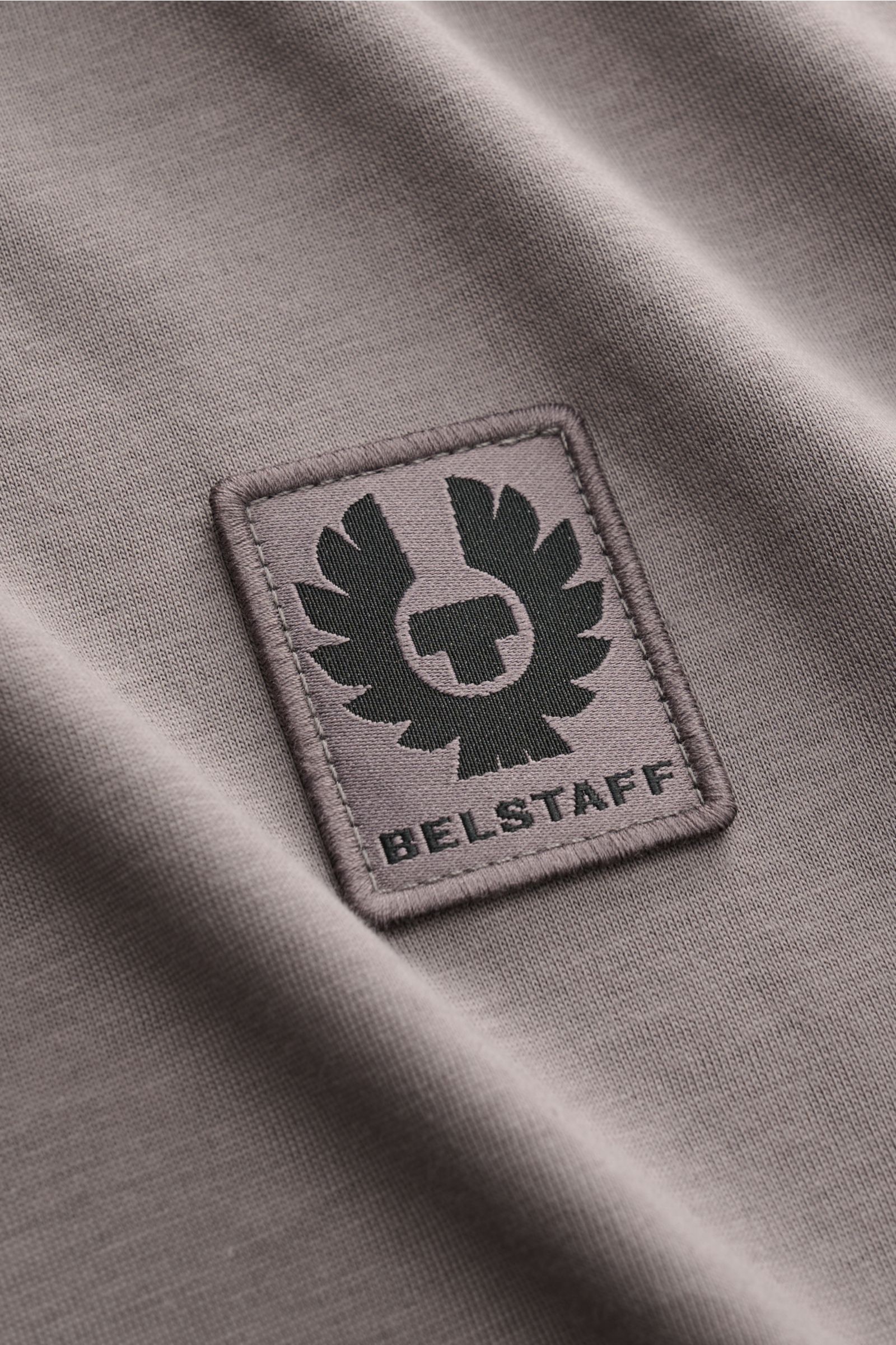 Close-up of the tonal Belstaff logo patch on the soft, lightweight cotton jersey fabric of the Belstaff Rundhals-T-Shirt dunkelgrau, photographed from a top angle.

Description: Dieses T-Shirt von BELSTAFF, gefertigt aus leichtem Baumwoll-Jersey und ve