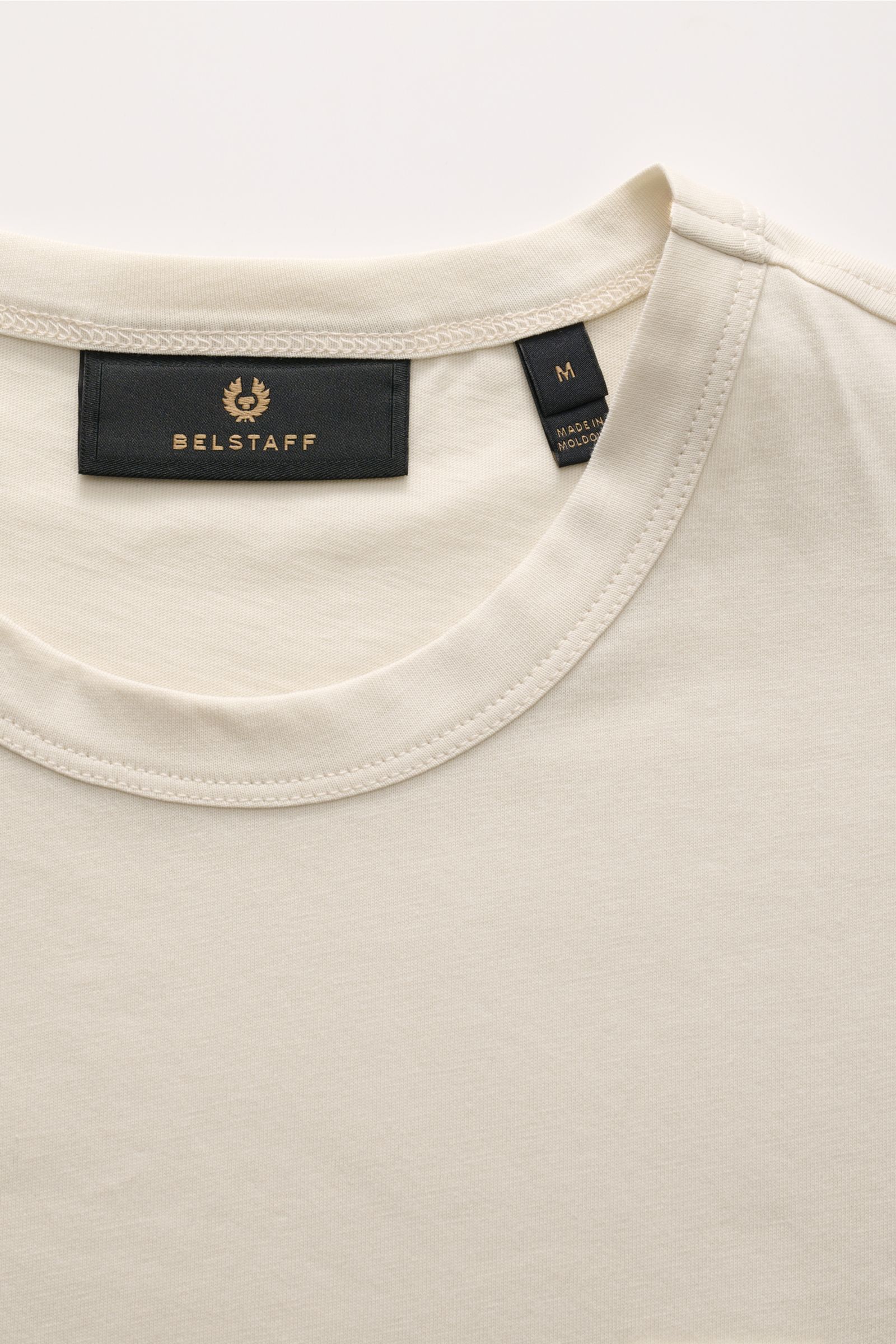 Belstaff Rundhals-T-Shirt creme aus weichem Baumwoll-Jersey mit Slim Fit, Rundhalsausschnitt und tonalem Belstaff-Weblabel, Nahaufnahme von oben.