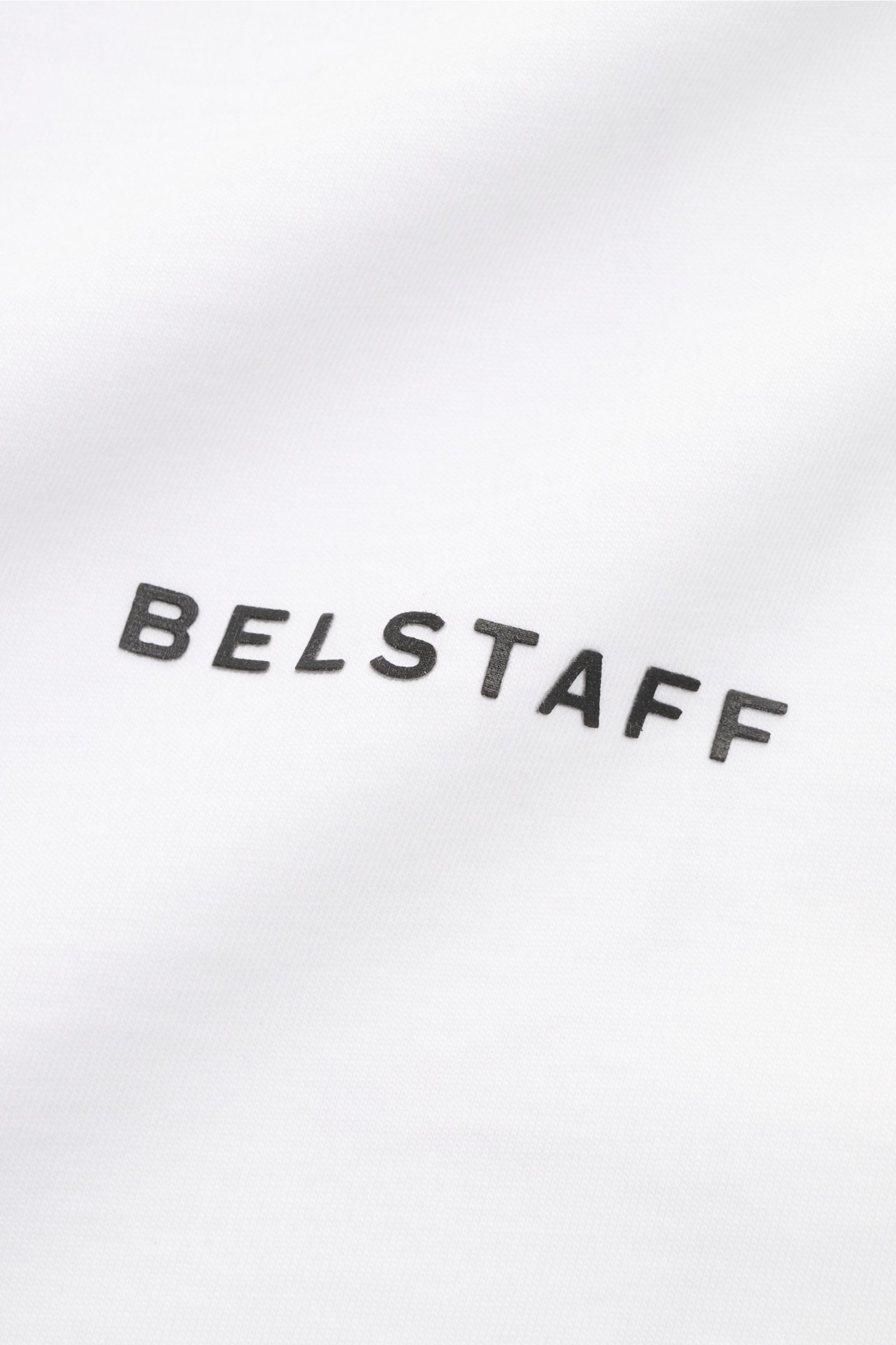 Close-up front view of the Belstaff Rundhals-T-Shirt 'Border' weiß showing the black BELSTAFF logo on white cotton jersey fabric. Das Rundhals-T-Shirt 'Border' von BELSTAFF zeigt sich im Regular Fit mit markantem XXL-Phönix-Logo auf dem Rücken – ein kl