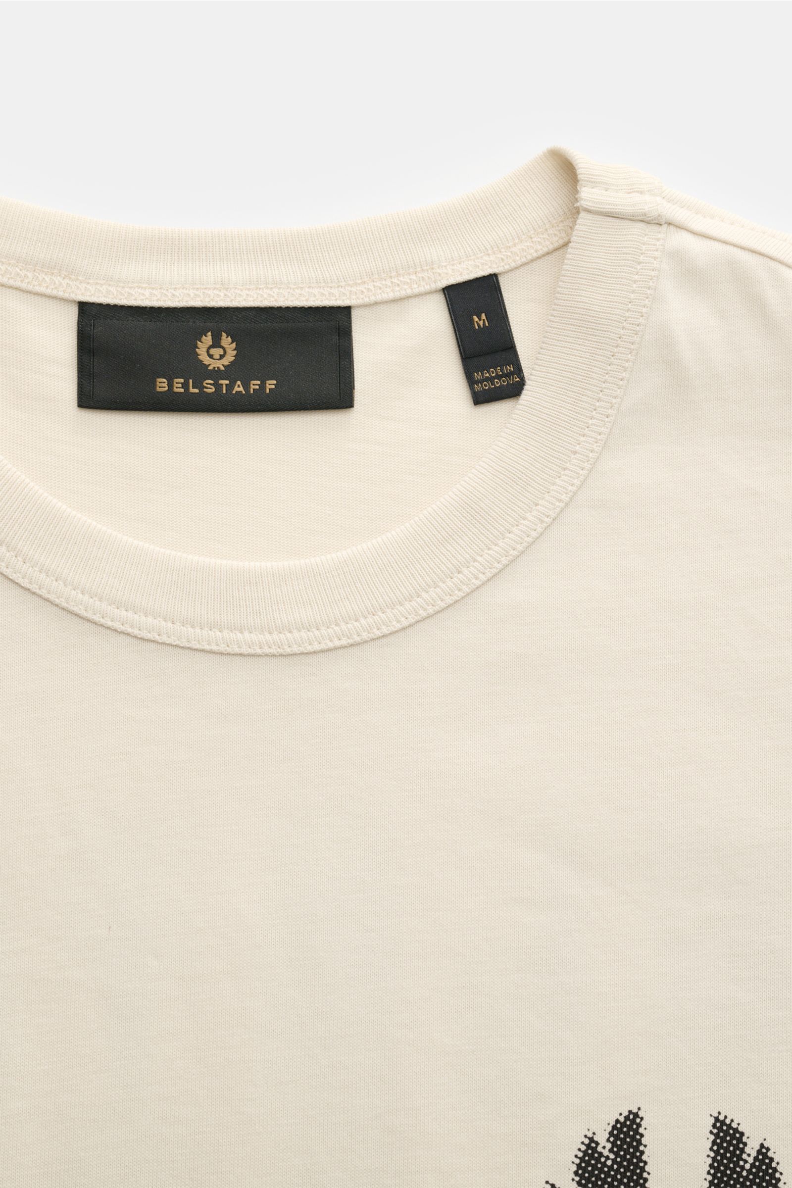 Belstaff Rundhals-T-Shirt 'Shadow' beige shown from a close-up front-top perspective, made of soft cotton jersey with a round neckline, featuring the black Belstaff label and size tag inside the collar. 

Das 'Shadow' T-Shirt von BELSTAFF ist ein viels