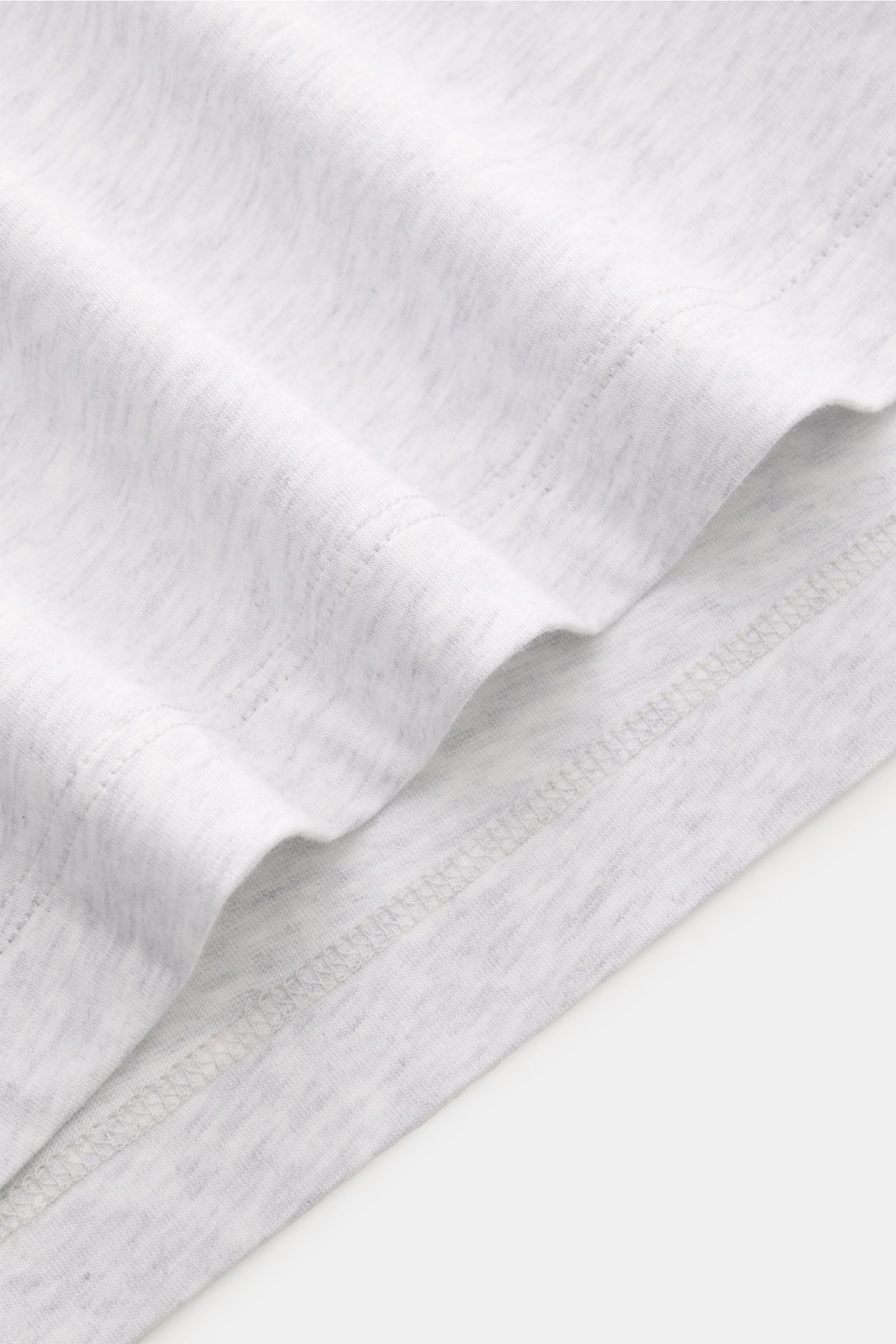 Close-up detail of the hem of the Brunello Cucinelli Rundhals-T-Shirt hellgrau meliert, showing fine stitching and soft light gray cotton jersey fabric from a side perspective.

Luxuriöse Materialqualität und feinste Verarbeitung verleihen dem Rundhals
