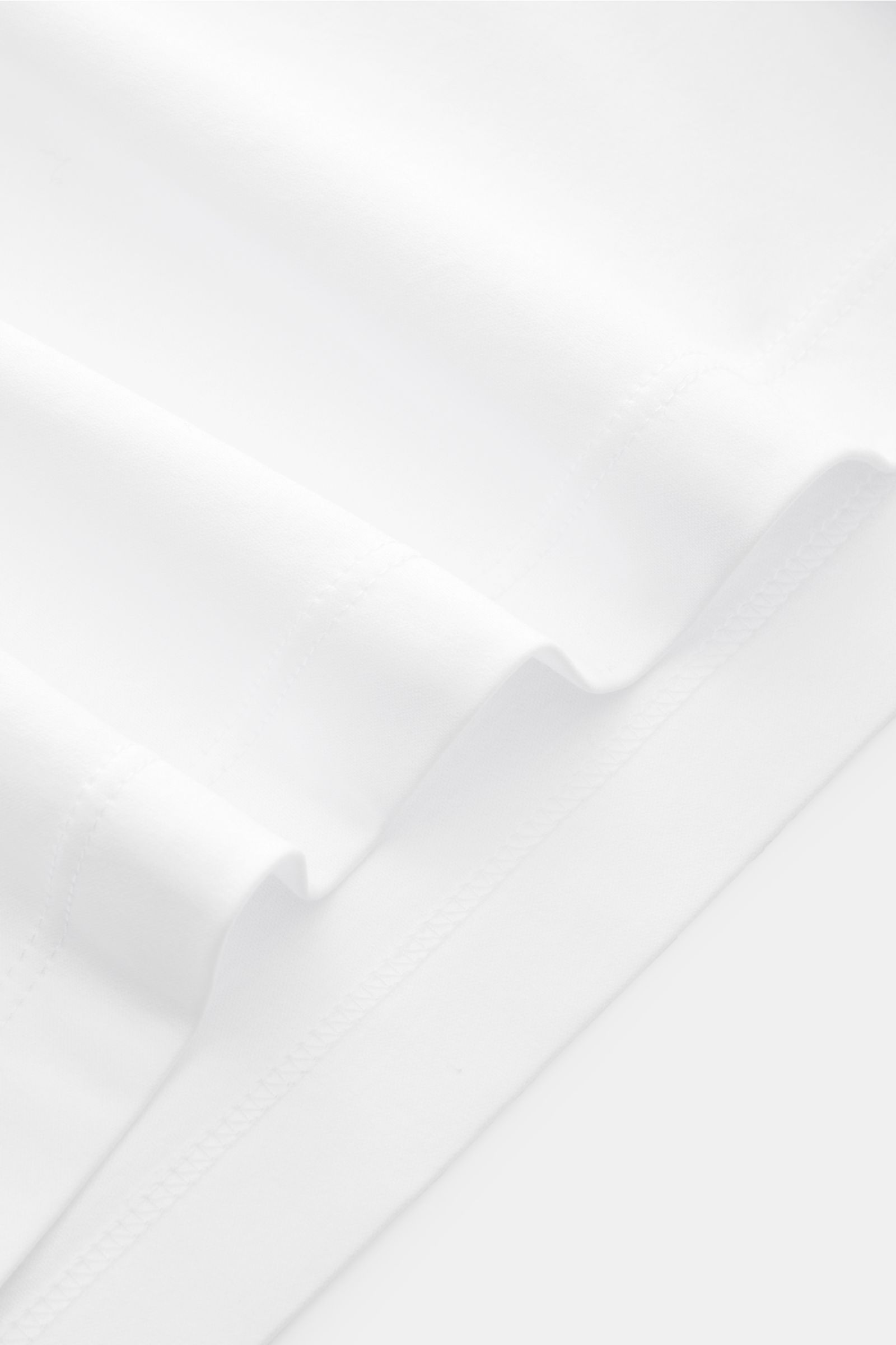 Close-up angled view of the hem and stitching detail on the white Brunello Cucinelli Rundhals-T-Shirt weiß, showcasing luxurious cotton jersey fabric.

Luxuriöse Materialqualität und feinste Verarbeitung verleihen dem Rundhals-T-Shirt aus reinem Baumwo
