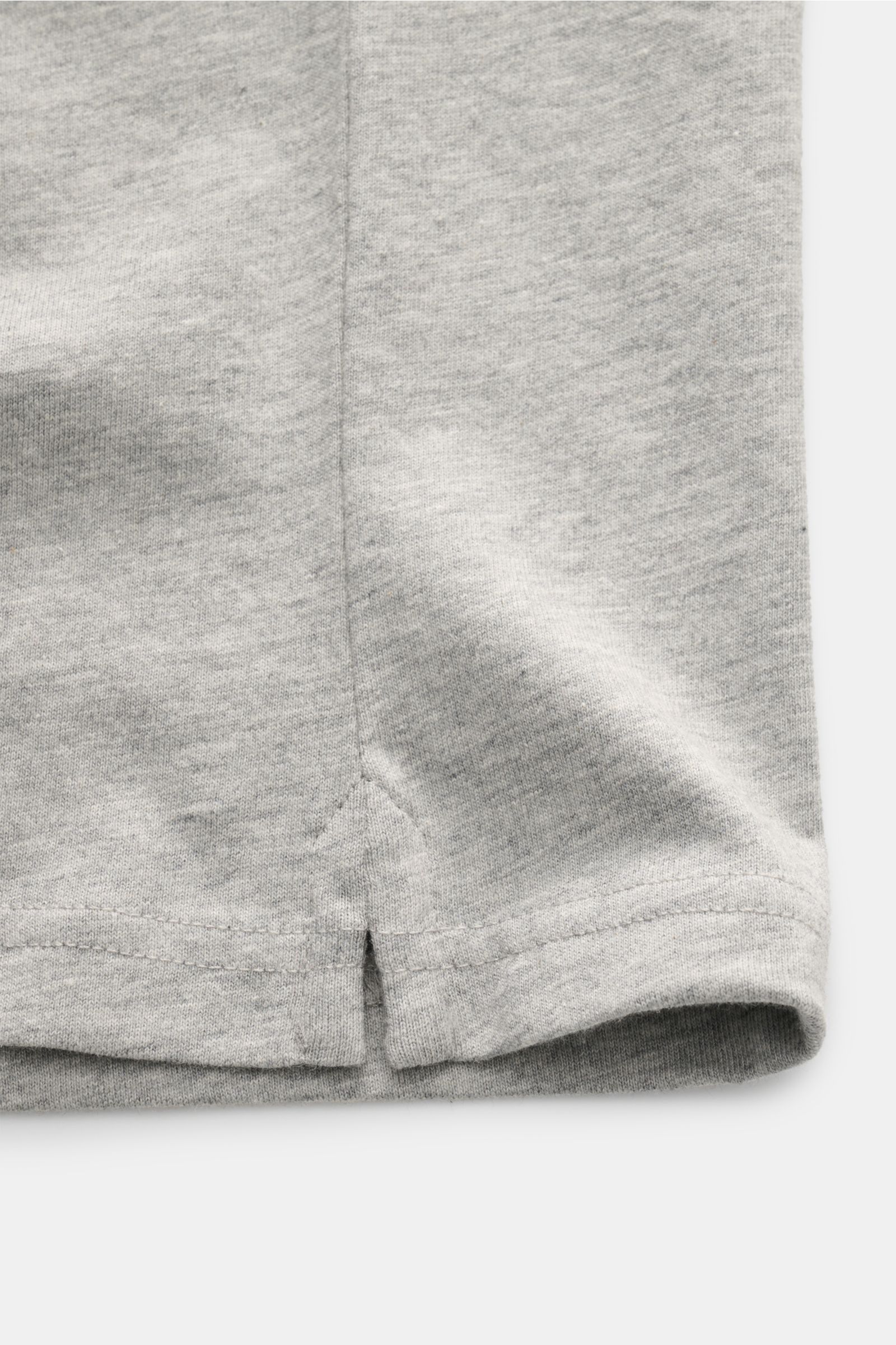 Close-up of the hem with short side slit of the Closed Rundhals-T-Shirt grau meliert, photographed from a top-down perspective, showing soft, pure cotton fabric with a regular fit and round neckline.