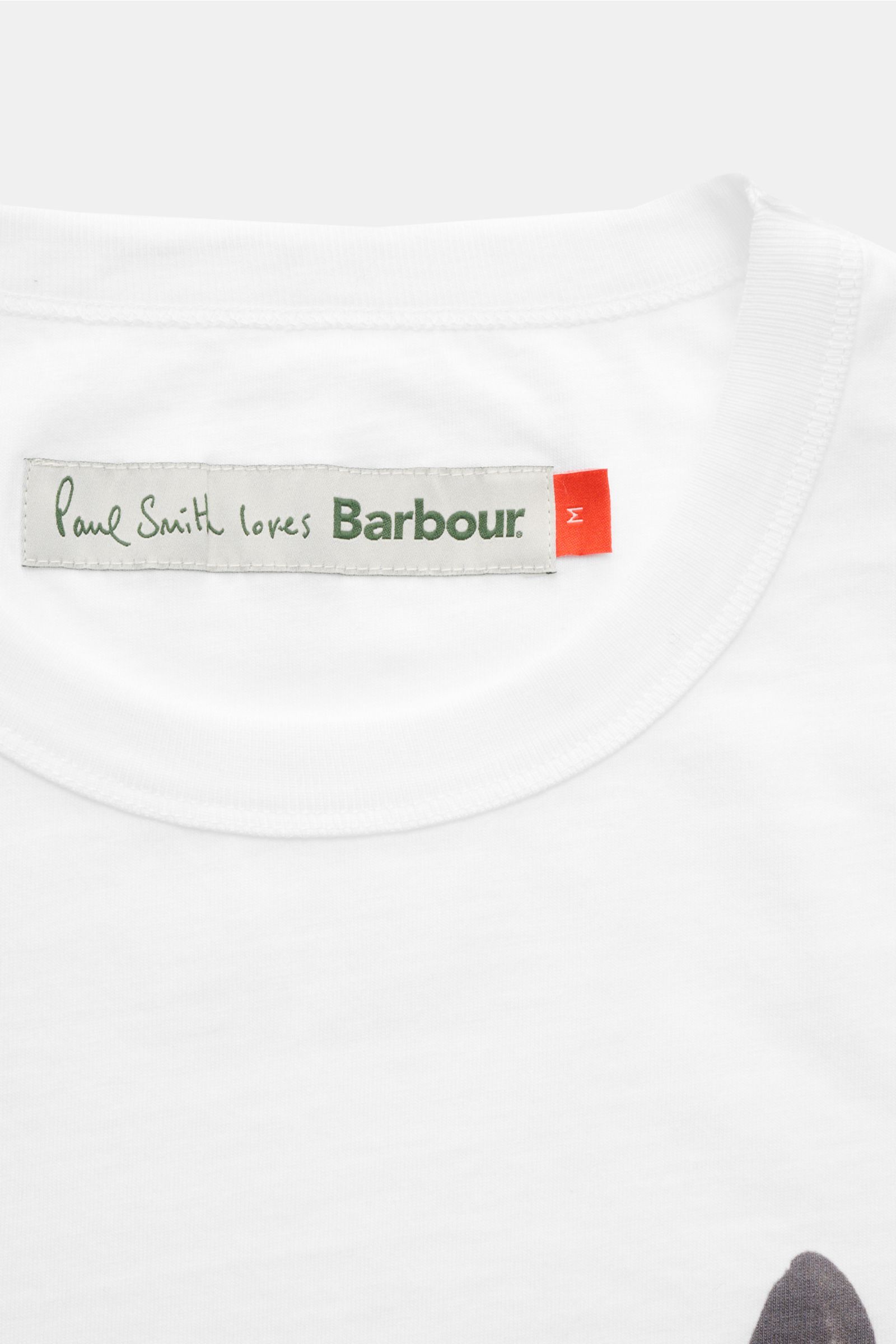 Barbour Rundhals-T-Shirt weiß shown from a close-up top-front perspective, featuring a soft cotton fabric, Regular Fit, bold cow print, and rear woven label. Cooler Hingucker von BARBOUR aus der PAUL SMITH Kooperation: Dieses T-Shirt mit plakativem Kuh-Pr