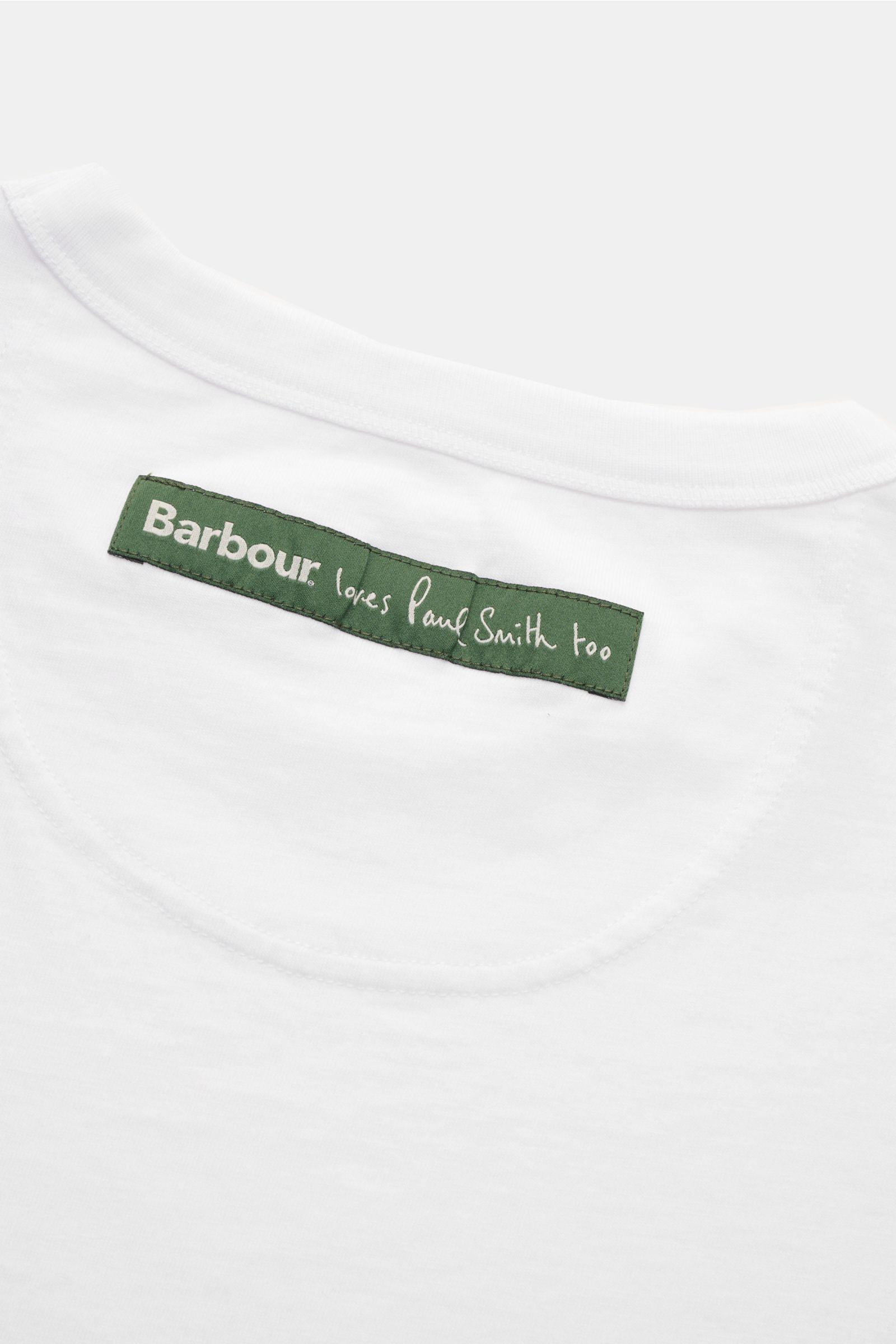 Close-up back view of Barbour Rundhals-T-Shirt weiß showing white fabric with green sewn-on label 'Barbour loves Paul Smith too,' made of pure cotton, soft quality, regular fit, with a striking cow print and rear woven label.

Description:
Cooler Hingu