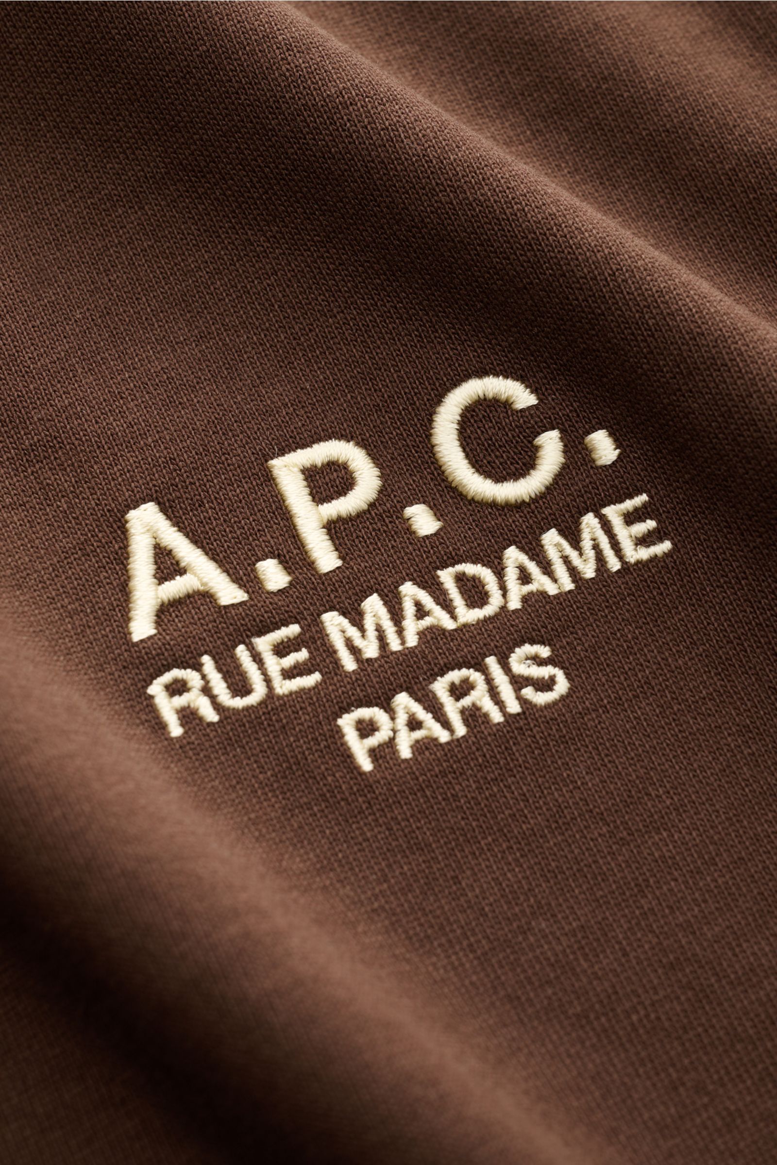Nahaufnahme des braunen A.P.C. Rundhals-T-Shirts 'Standard Rue Madame' mit weichem Baumwoll-Jersey und kontrastierender Logo-Stickerei auf der Brust.